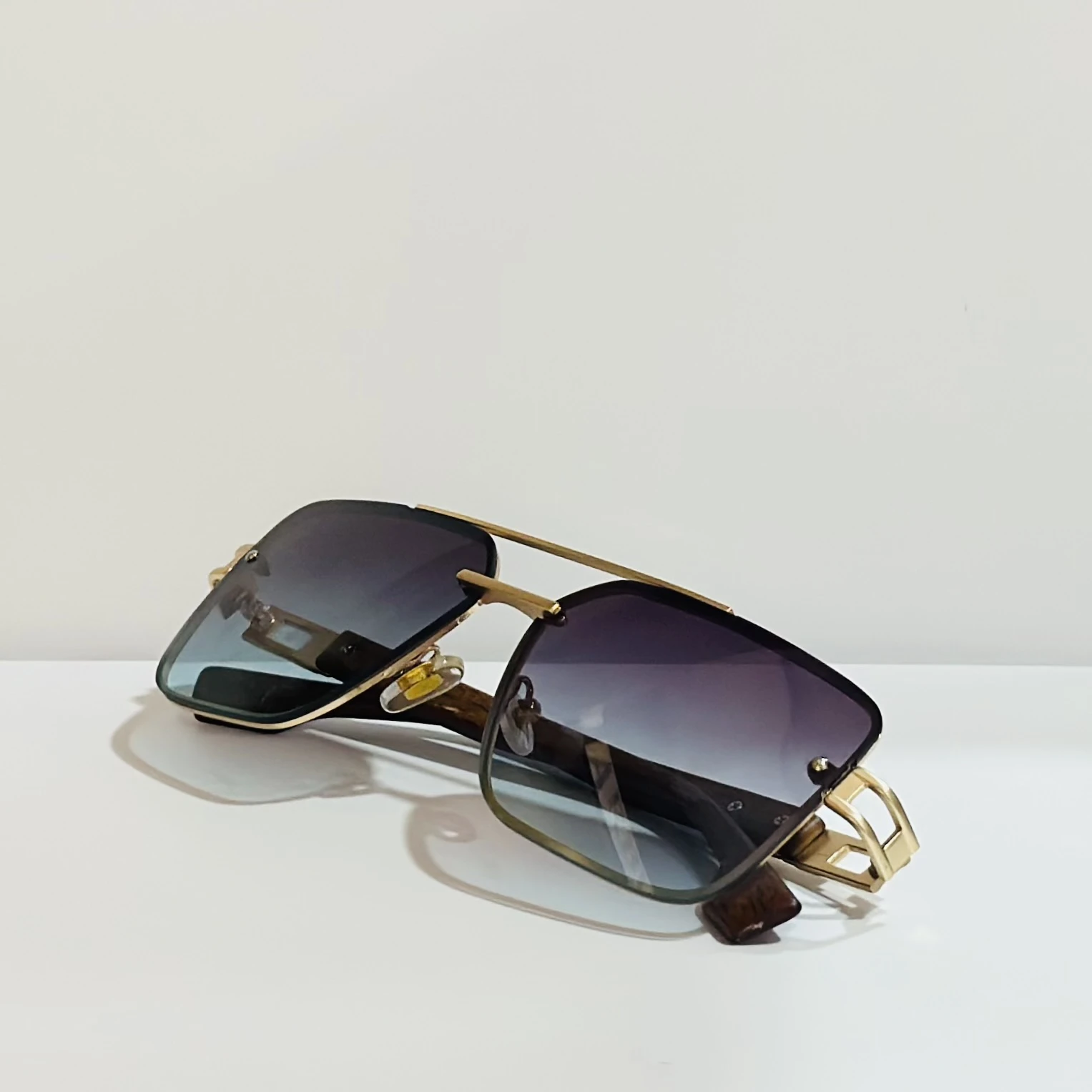 Pair of of aviator-style sunglasses with a gold-tone metal frame and blue gradient lenses.
