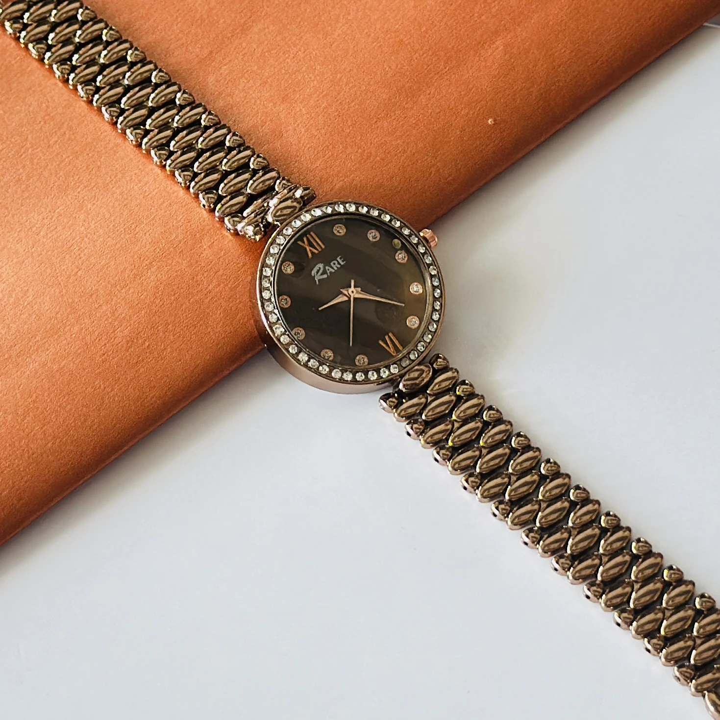 Rare analog watch with a bronze-toned metal bracelet and embellished dial.