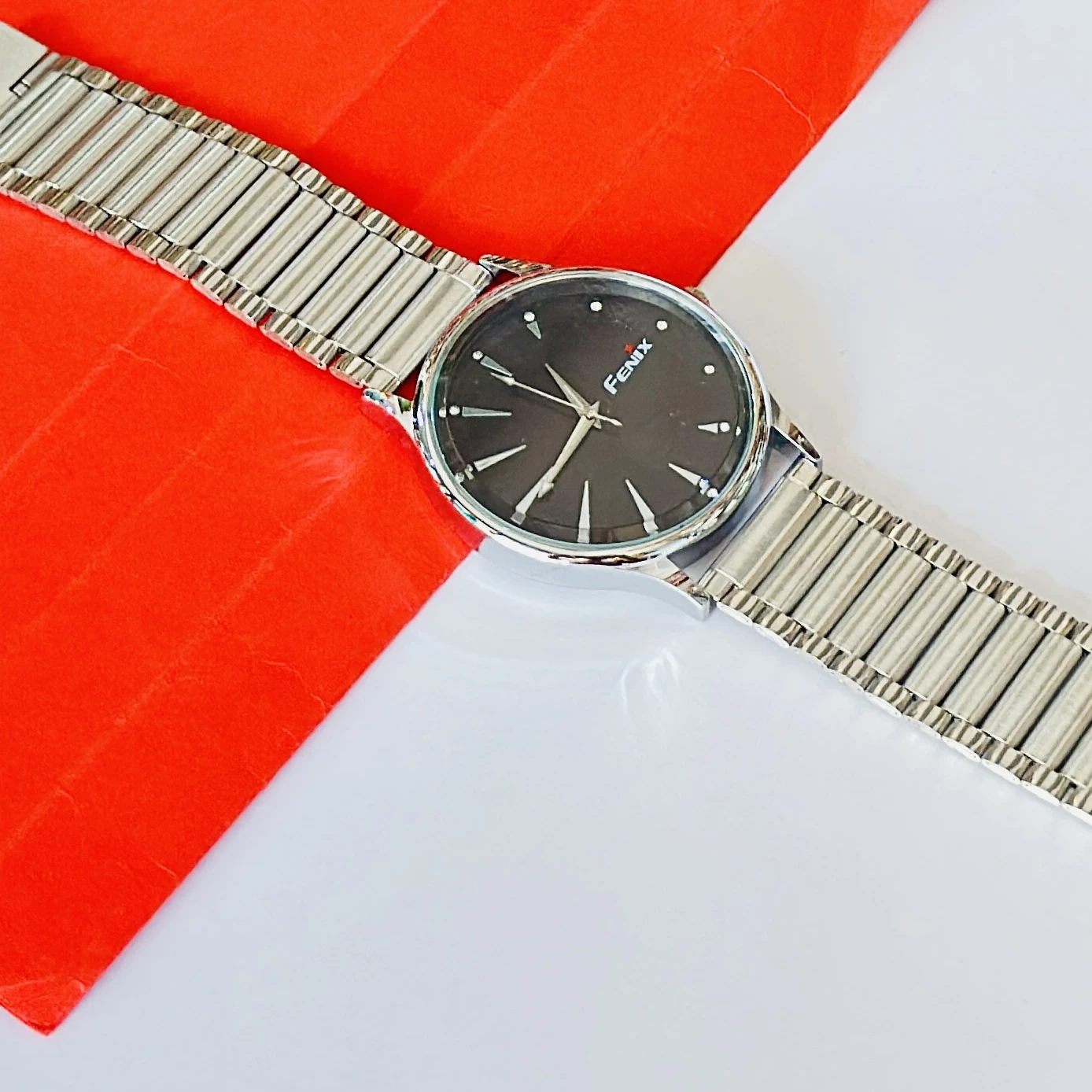 Analogue timepiece with a black dial and a silver stainless steel strap.