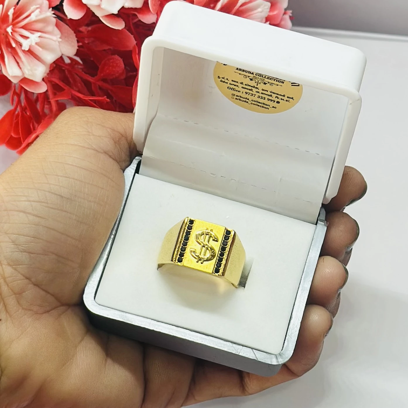Gold toned men's ring featuring a dollar sign emblem and black accents.