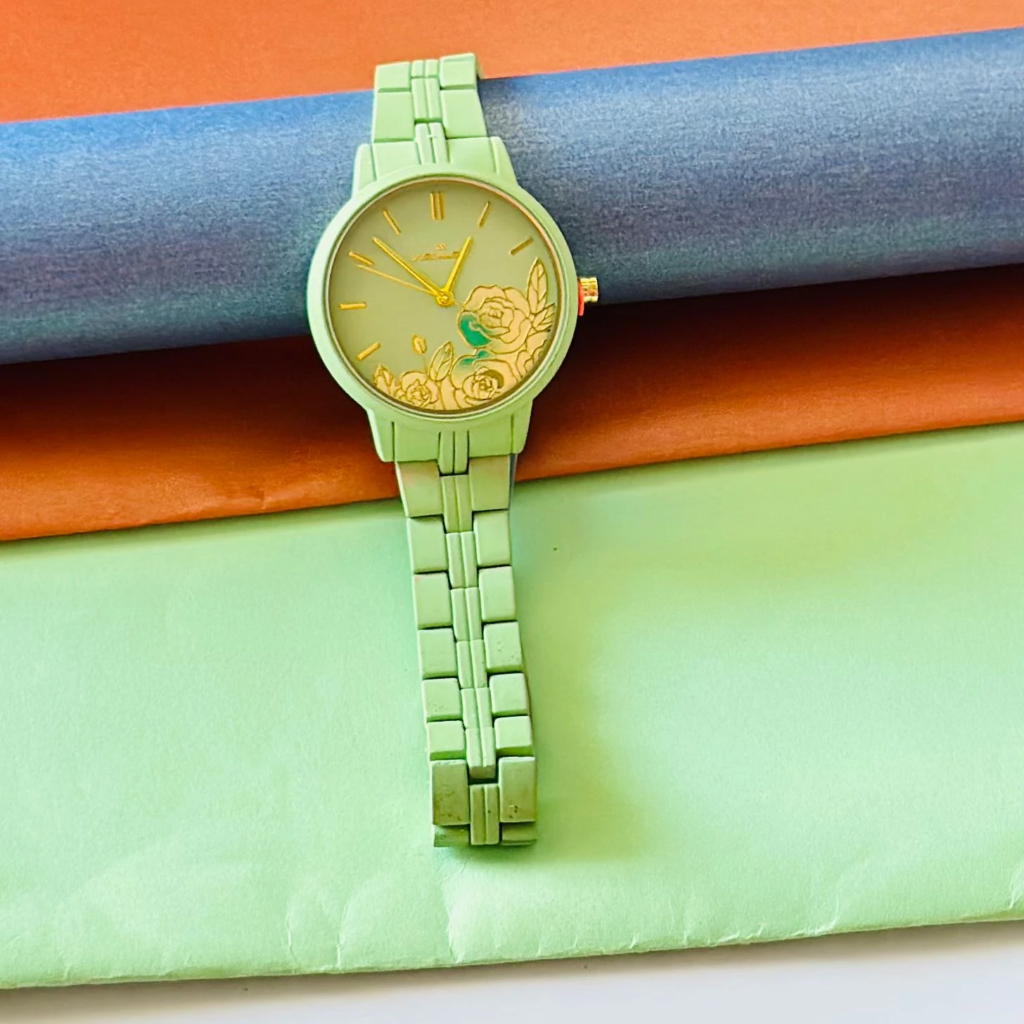 light green women's analog watch with a floral print on the dial and a link bracelet.