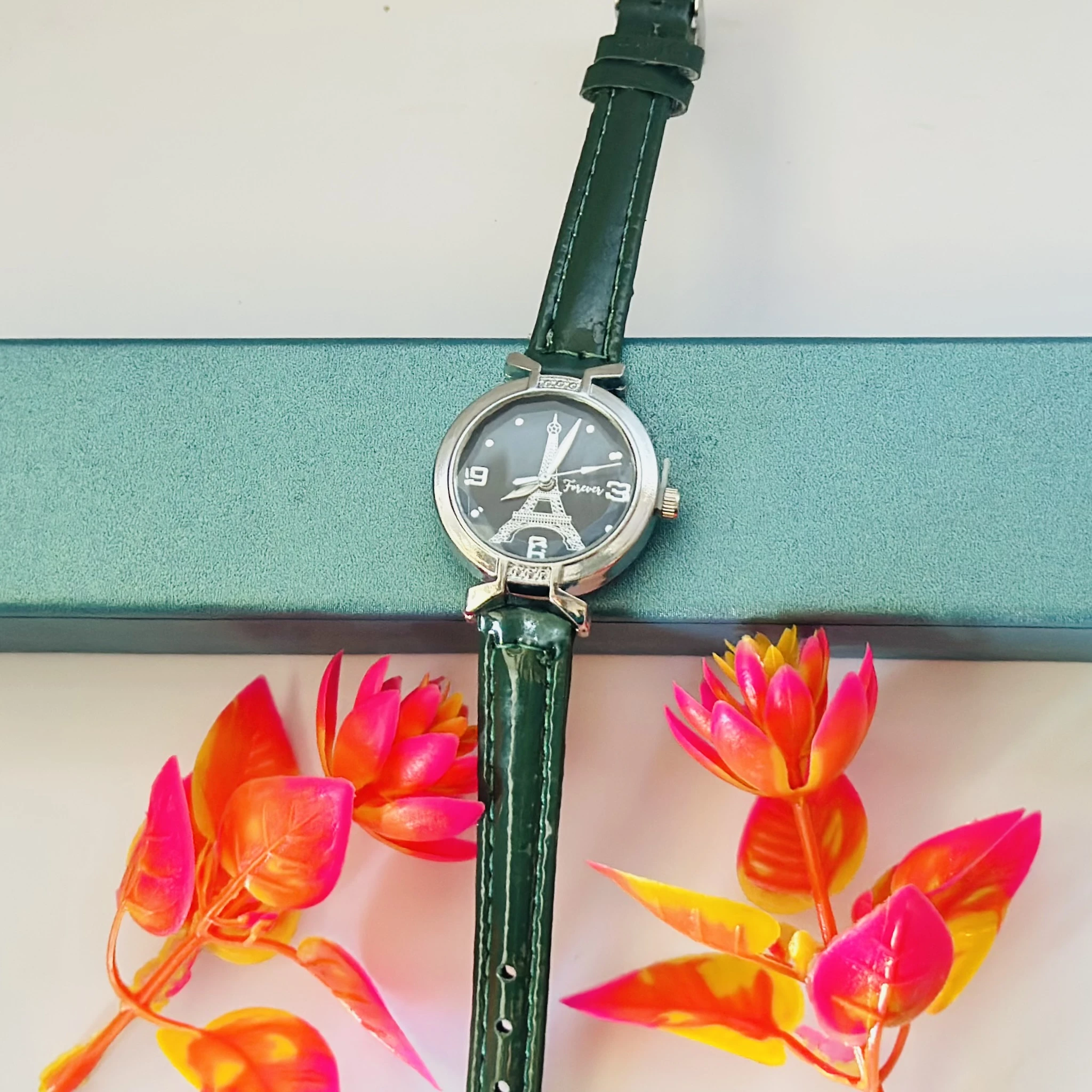 women's analog watch featuring an Eiffel Tower design and a green leather strap.