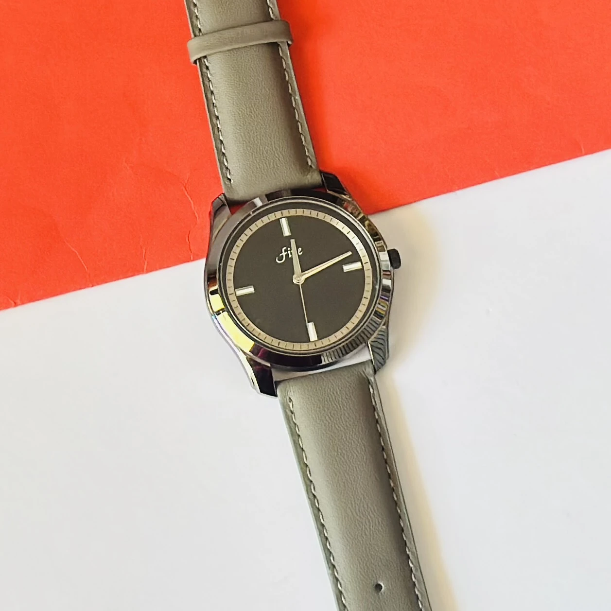 watch with a gray leather strap and a black dial.