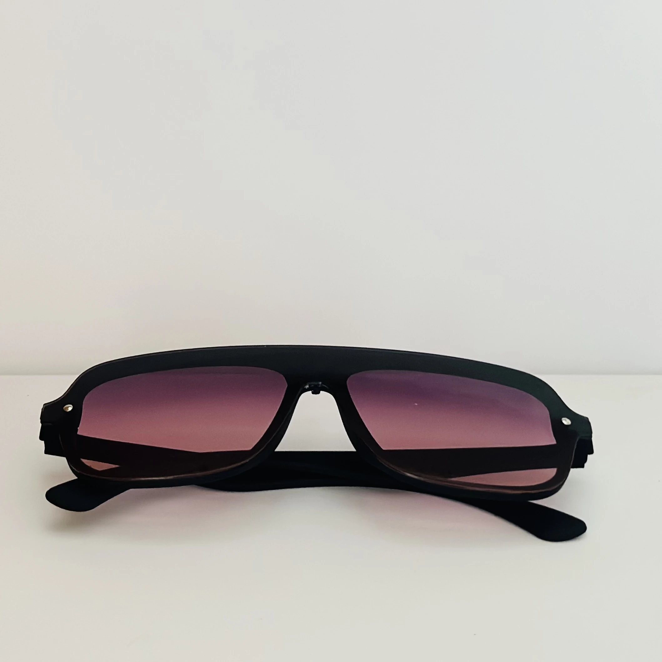 Black frame aviator-style sunglasses with pink gradient lenses.