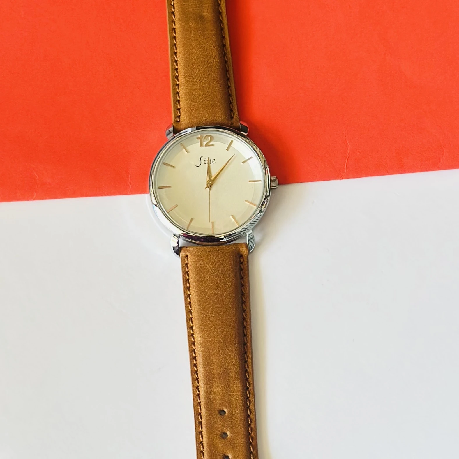 minimalist analog watch with a white dial, gold-tone case, and a brown leather strap