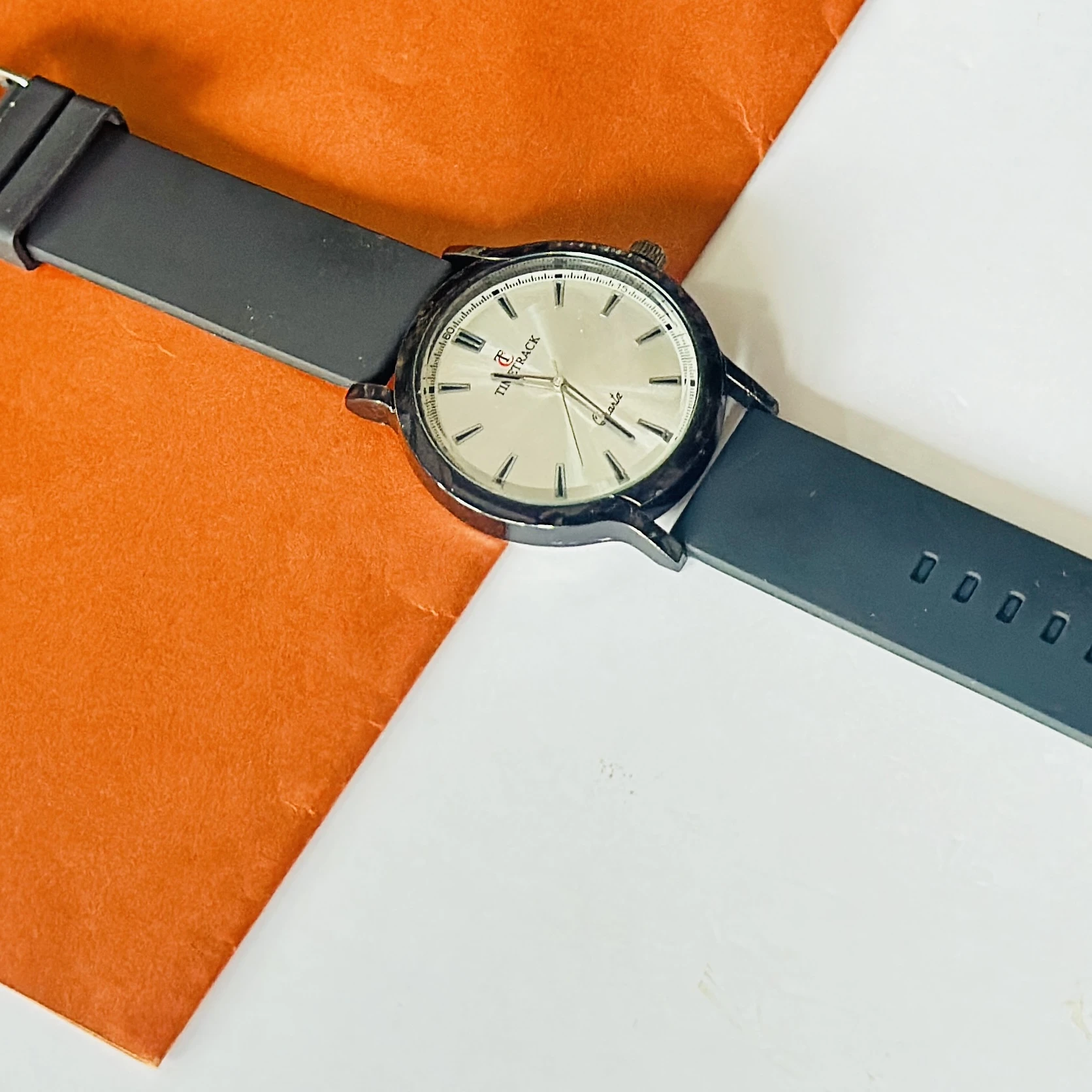 Timitrack brand quartz analog wristwatch with a silver-toned dial and a black silicone strap.