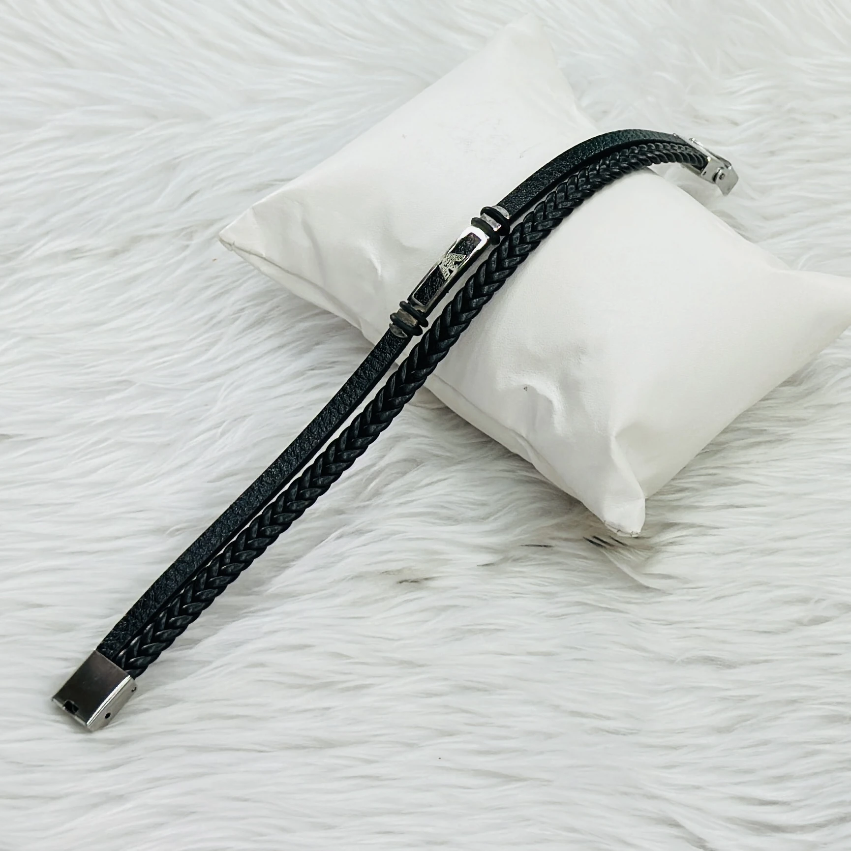 Jewelry bracelet features a black leather design paired with a stainless steel bar.