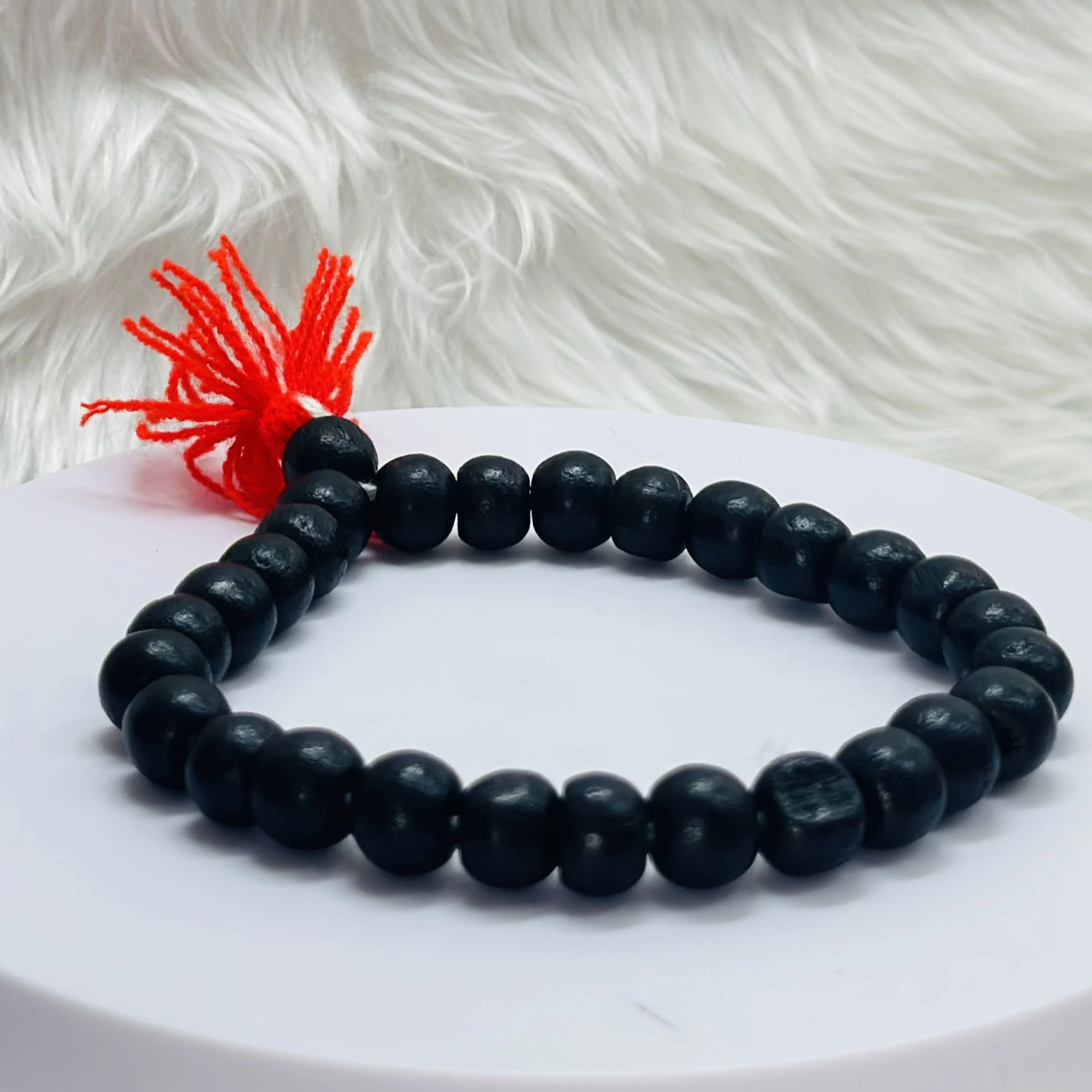 Black onyx or blackwood beaded bracelet with a red tassel.
