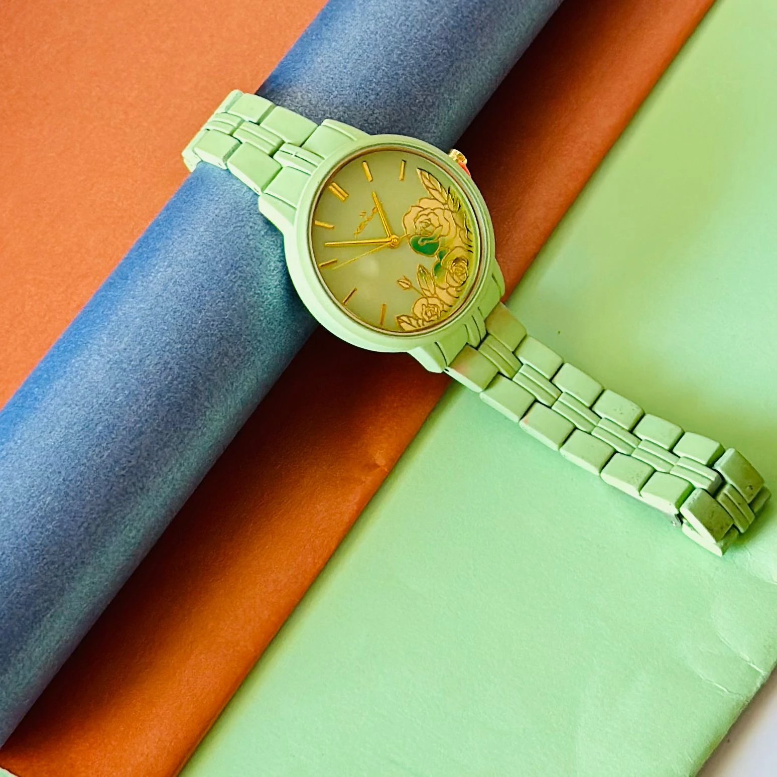 light green women's analog watch with a floral print on the dial and a link bracelet.
