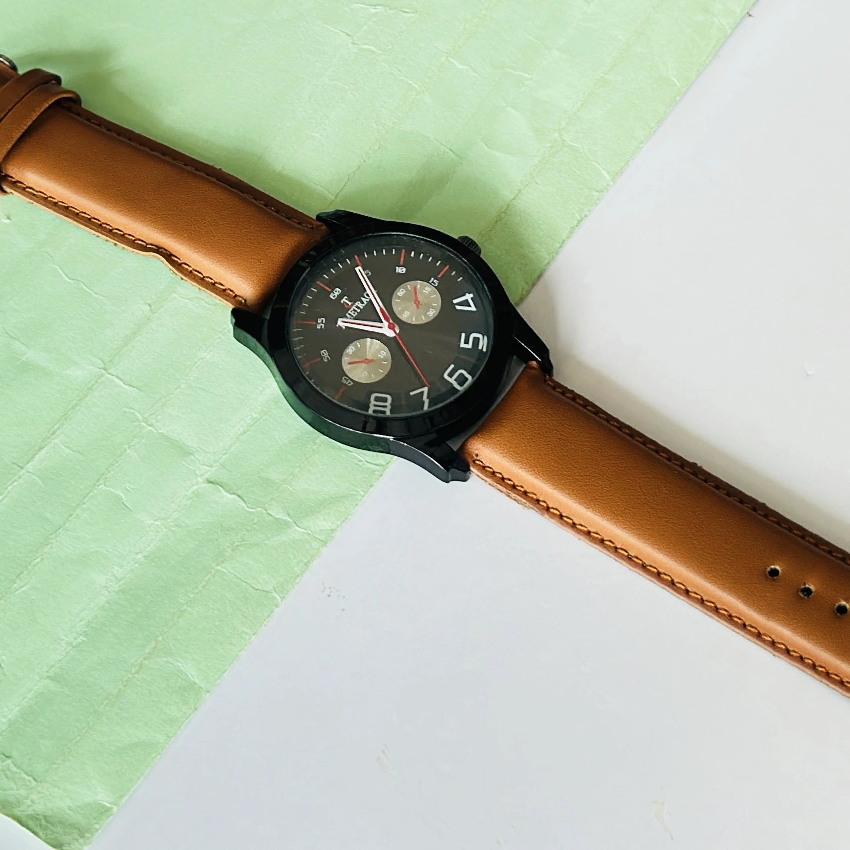 Titan Quartz Analog watch with a brown leather strap and a black dial.