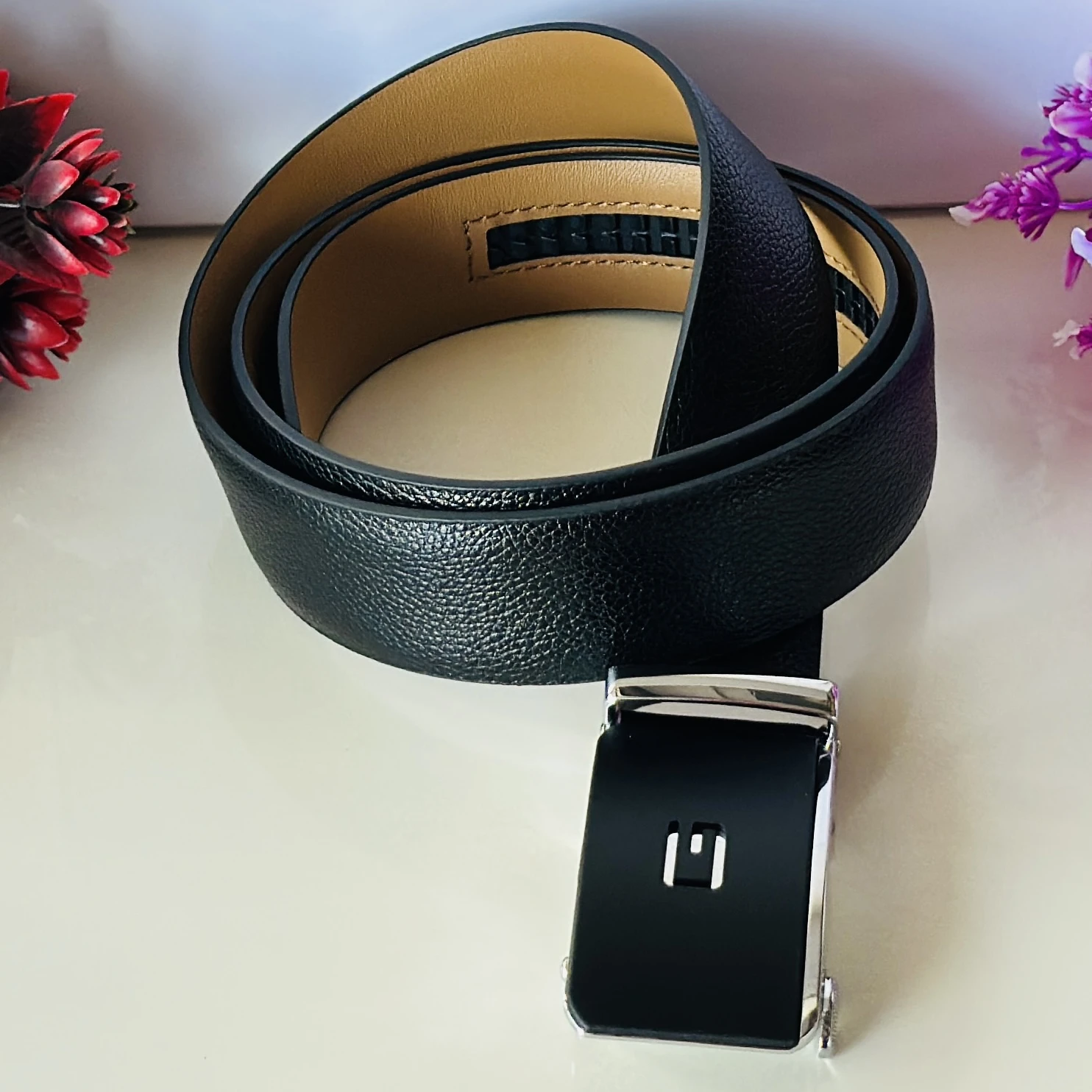 Black leather belt with an automatic/ratchet buckle.