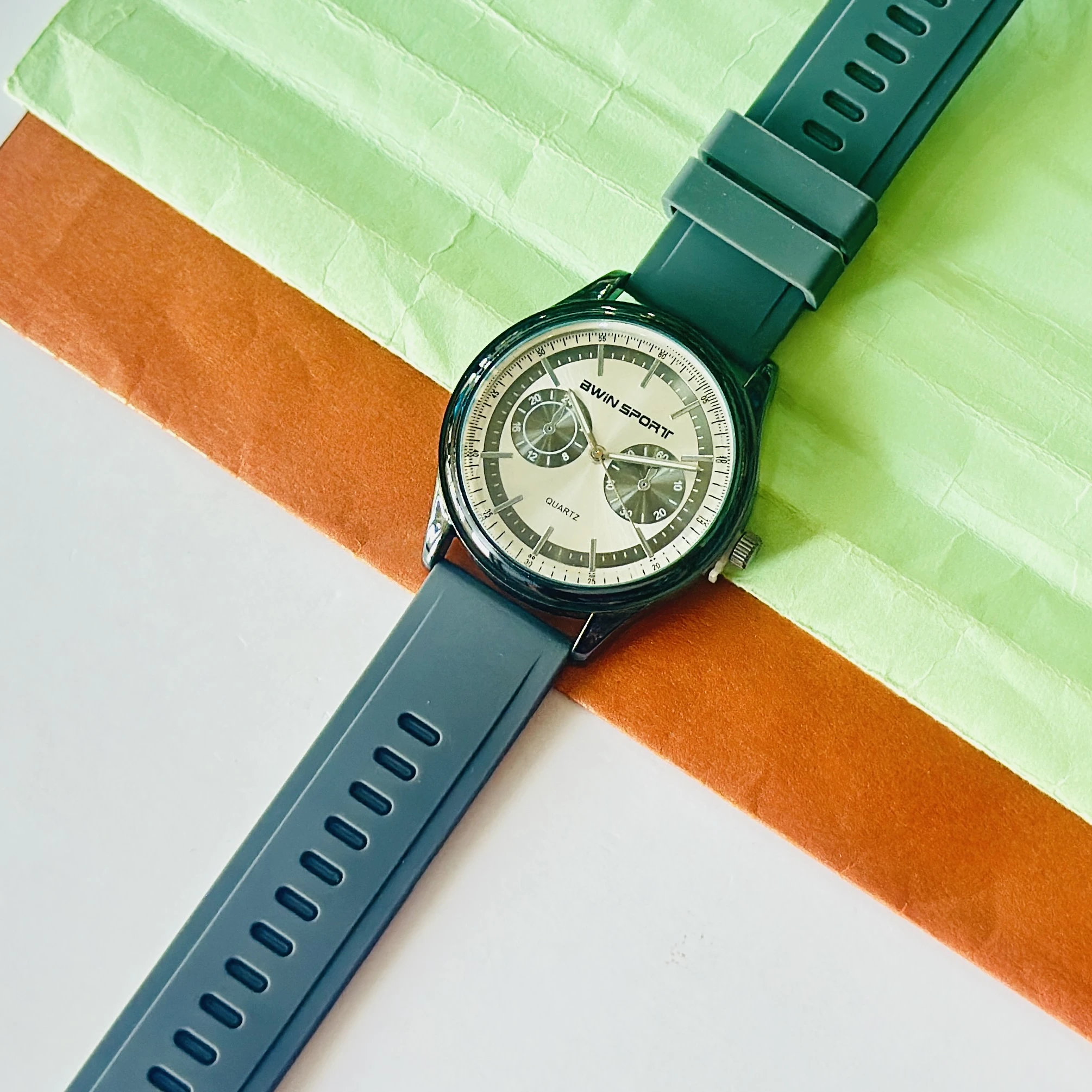 watch features a black dial with sub-dials and a green silicone strap.