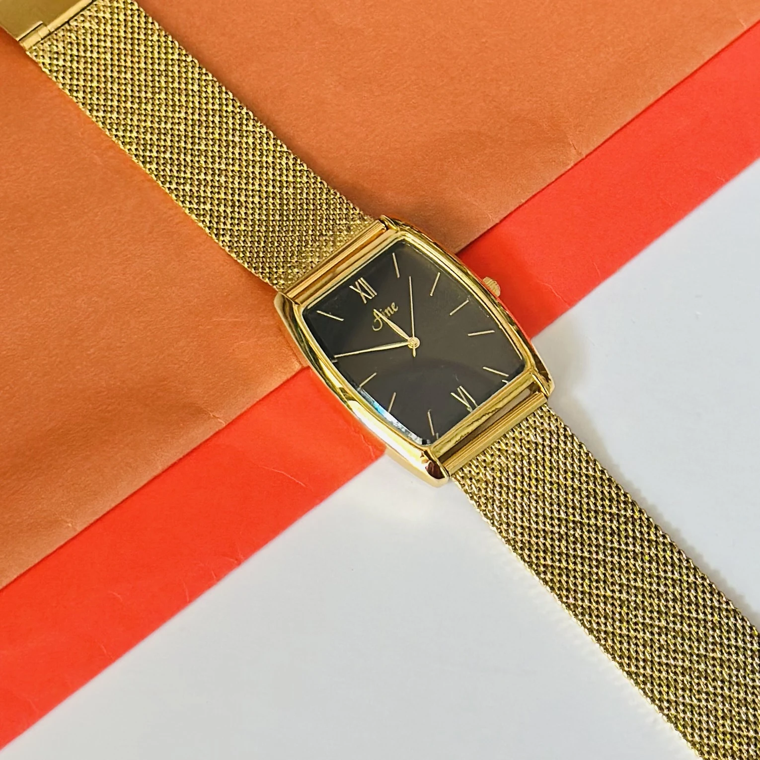 Aine vintage-style gold-tone rectangular quartz mesh watch with a black dial.