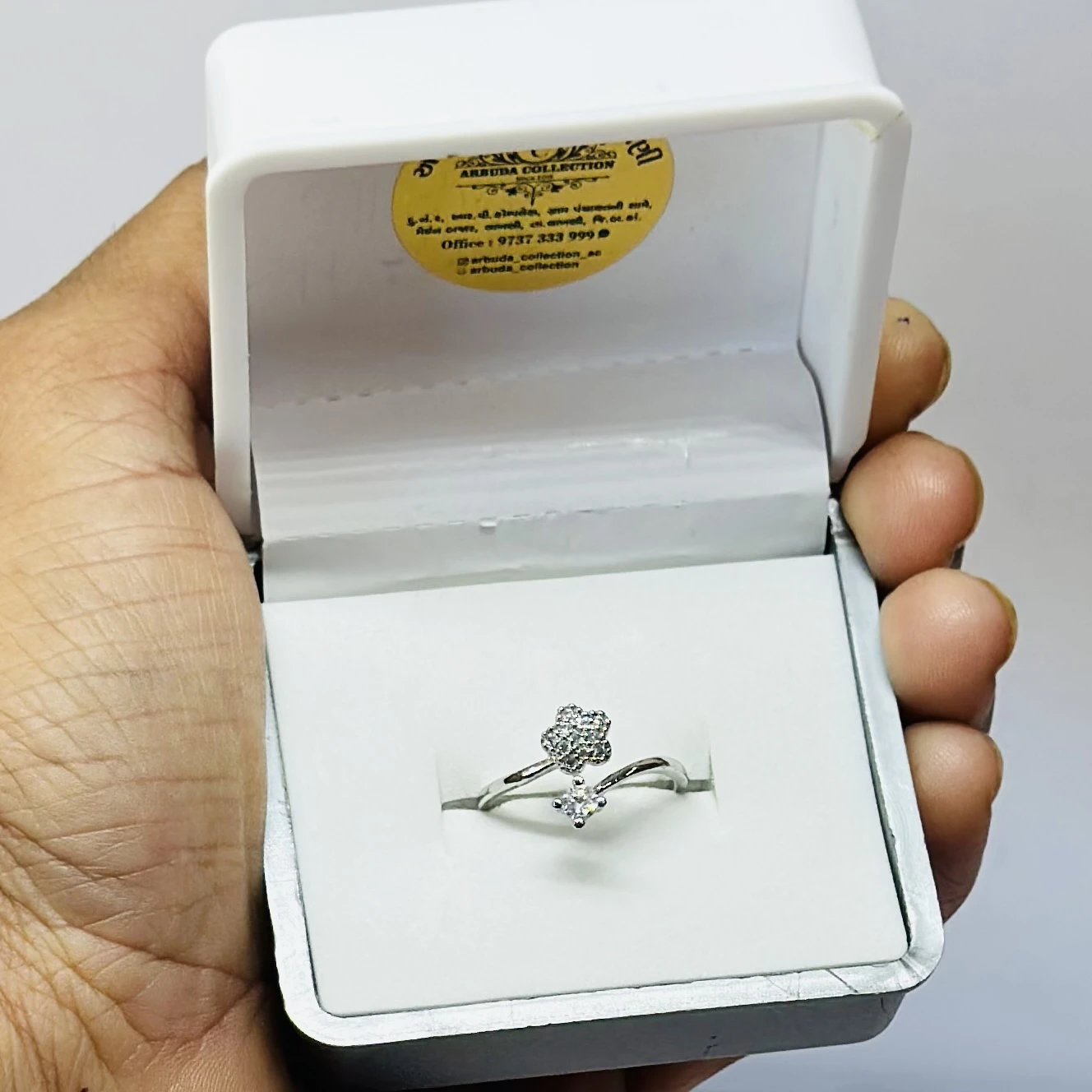 an adjustable silver-toned, stone-studded finger ring with a flower design.