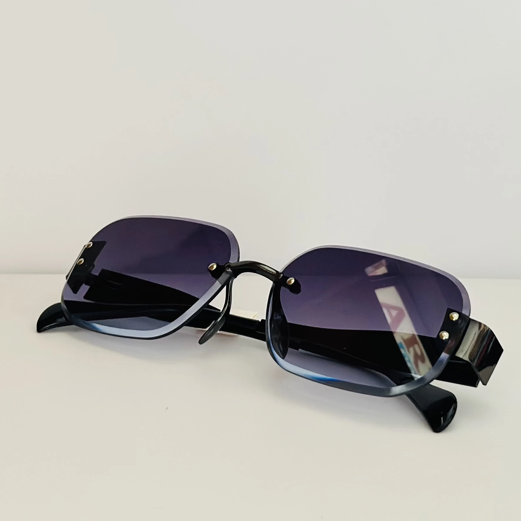 Frameless cut-edge sunglasses with black temples and a gradient tint.