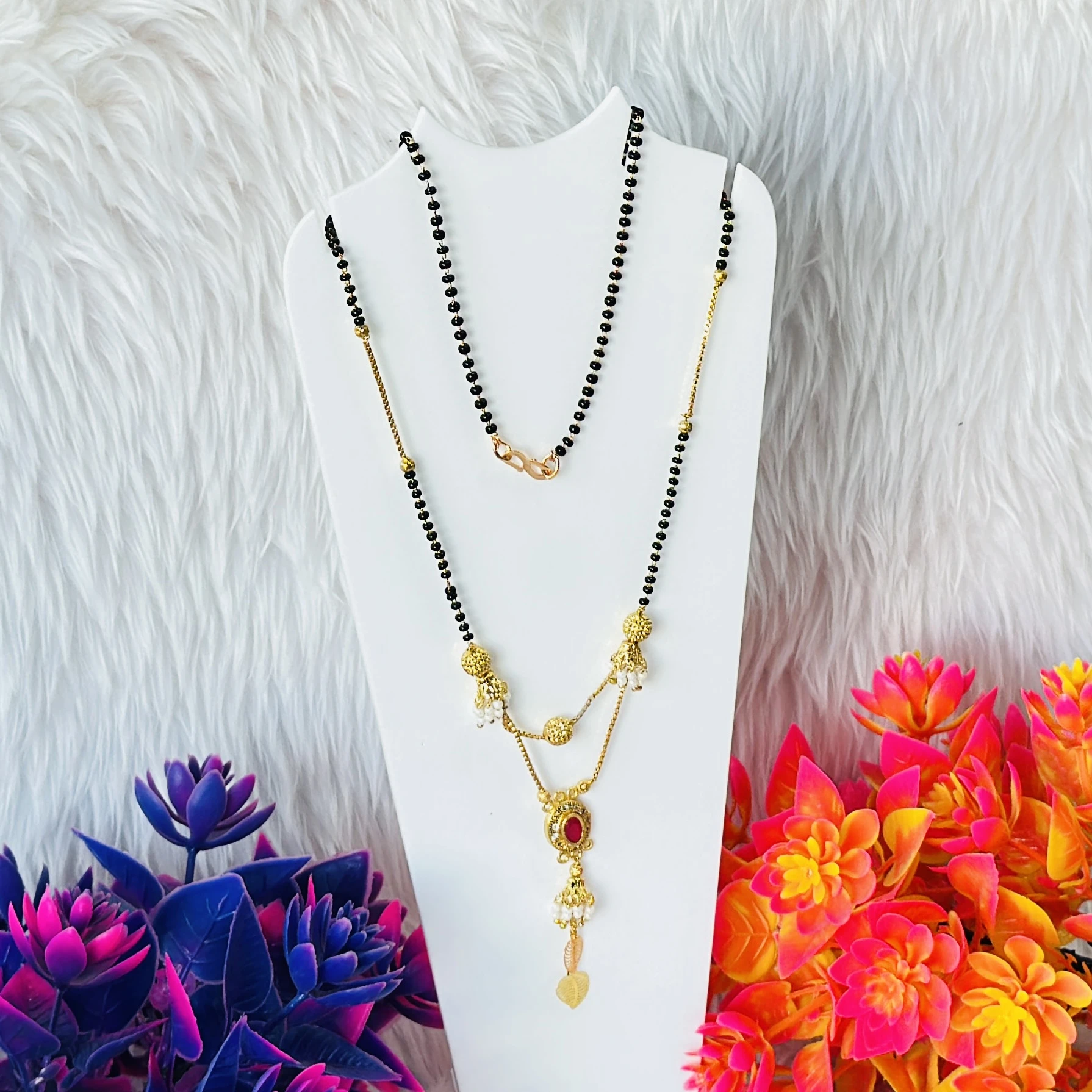 gold-plated mangalsutra with black beads and a red stone pendant.