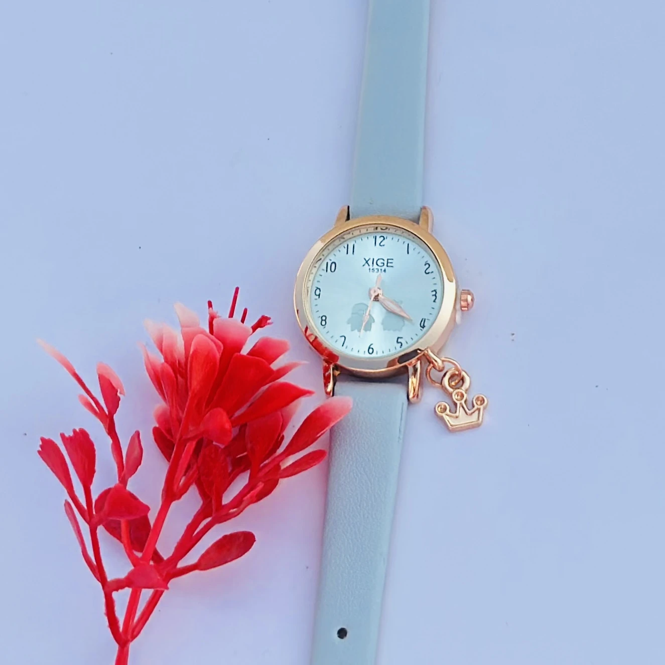 analog quartz watch with a rose gold case and a light blue leather strap featuring a horse charm.