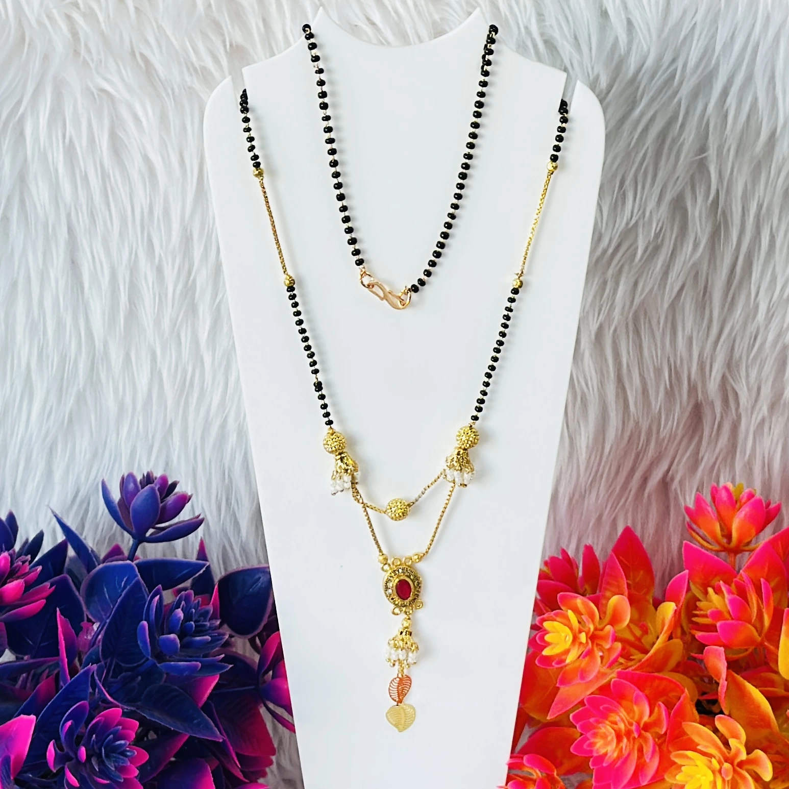 gold-plated mangalsutra with black beads and a red stone pendant.