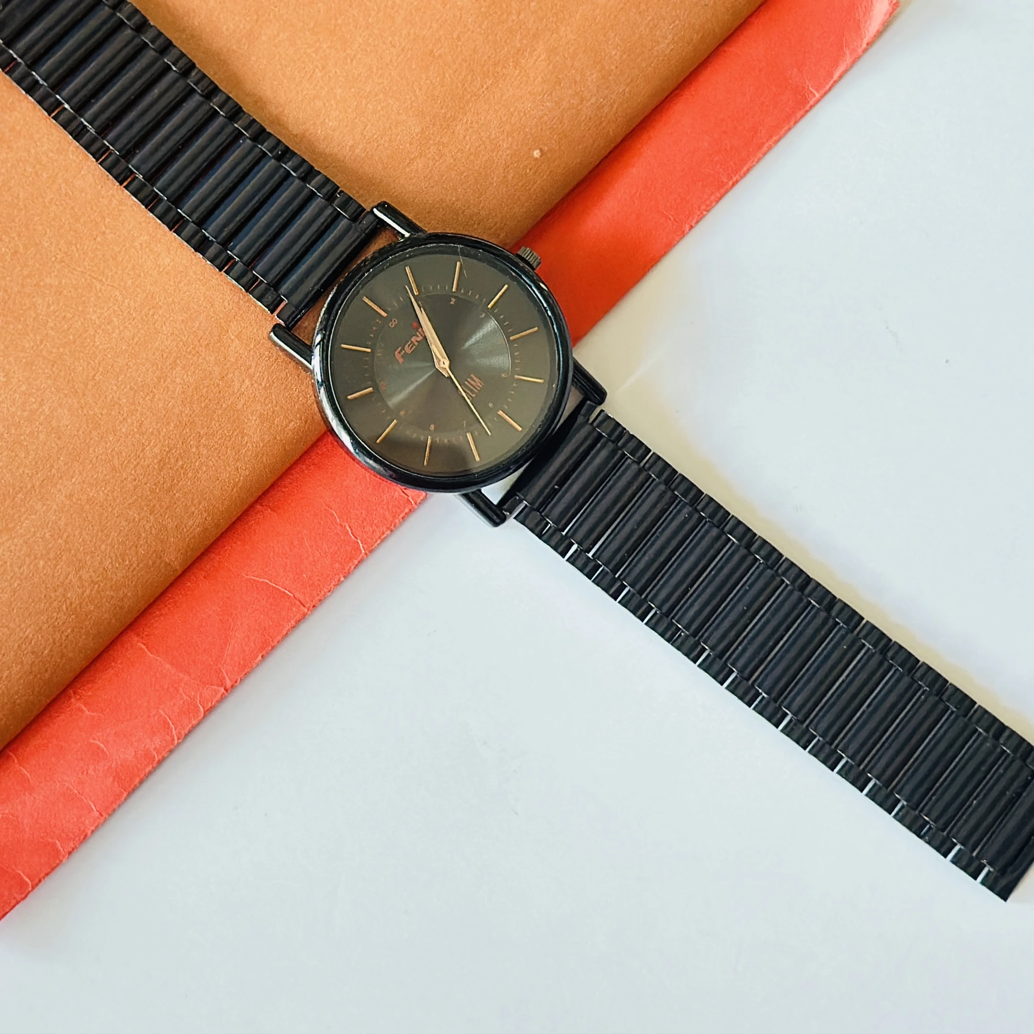 Black metal analog watch with a minimalist design and thin bracelet strap.