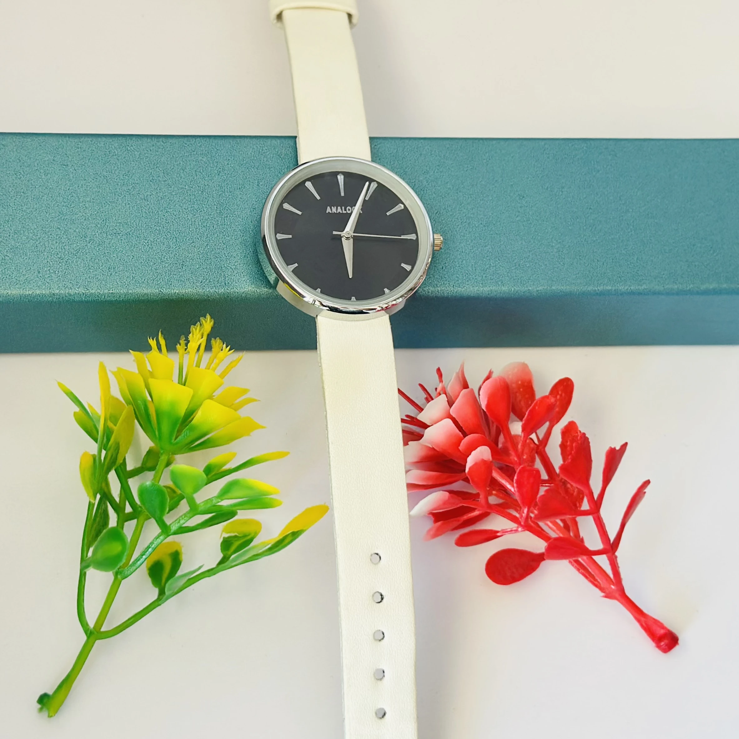 Analogue watch with a black face and a white band.