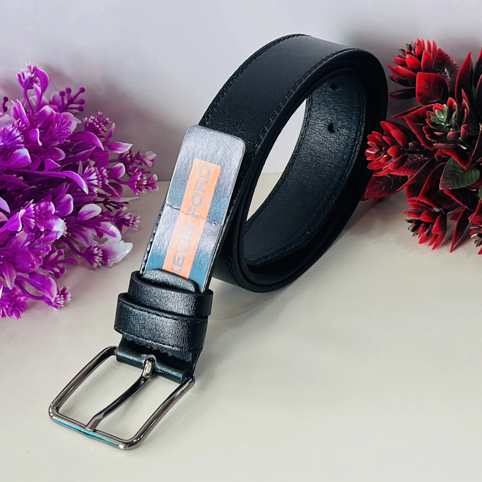 black belt with a silver-tone buckle and a "KEVIN FORD" label.