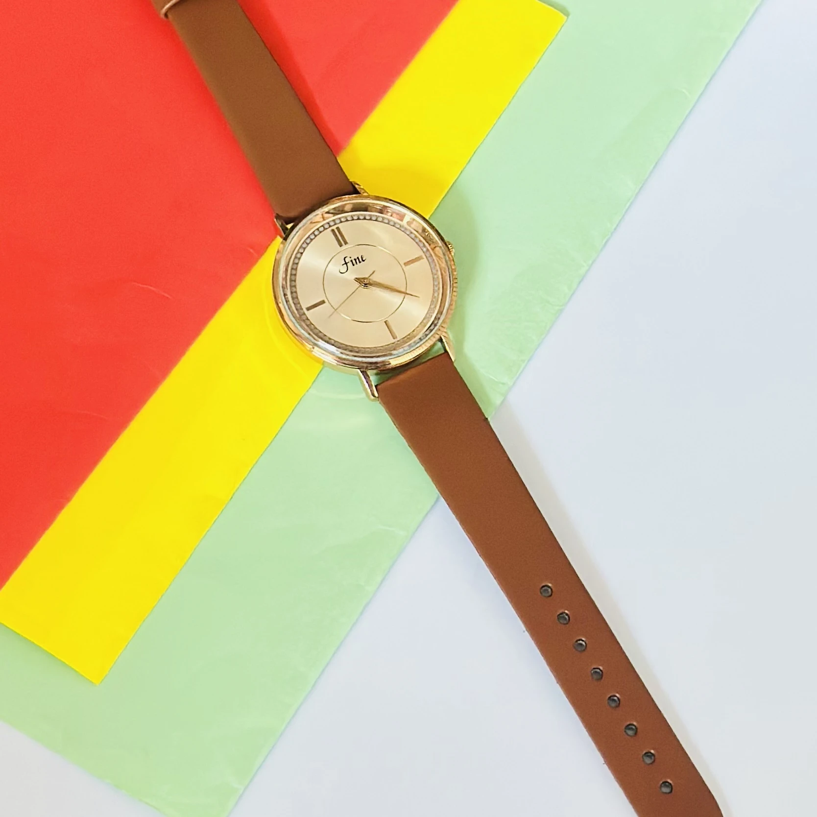 Gold tone analog wrist watch with a brown leather strap