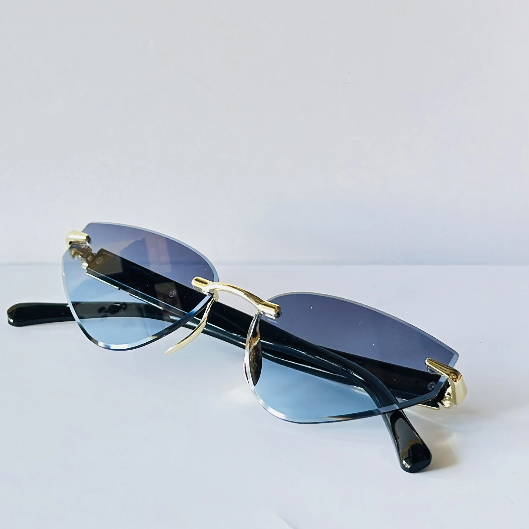 Rimless cat-eye sunglasses feature golden metal frame