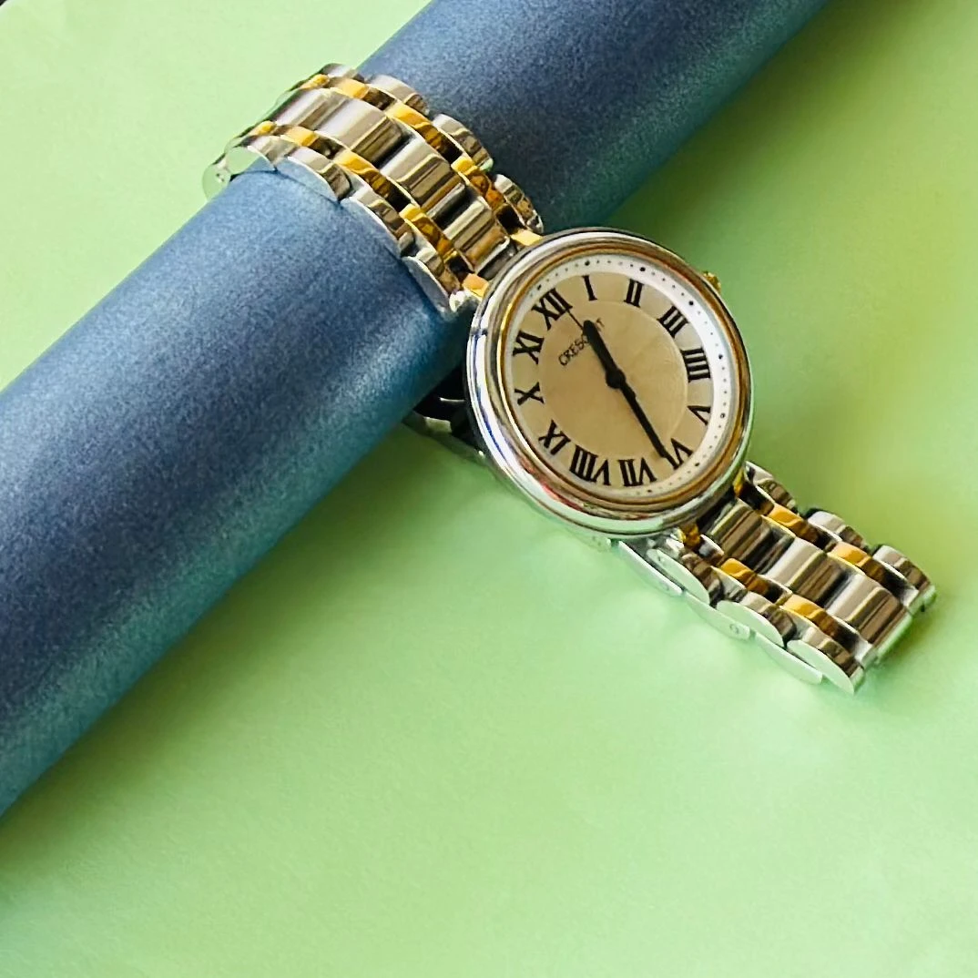 Crescent analog watch with a rectangular case and a two-tone (silver and gold) metal bracelet.