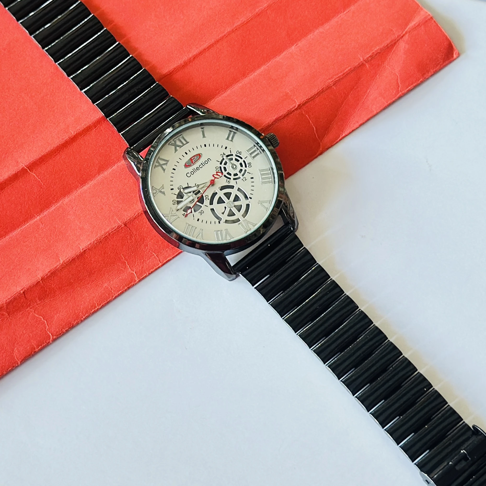 Black metal analog wristwatch with a white dial and roman numeral markers.