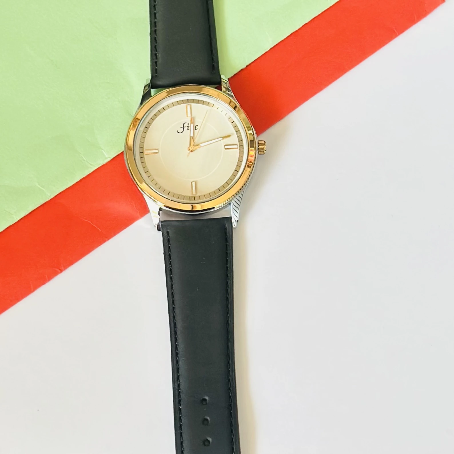 Analog wristwatch with a gold-tone case and a black leather strap.