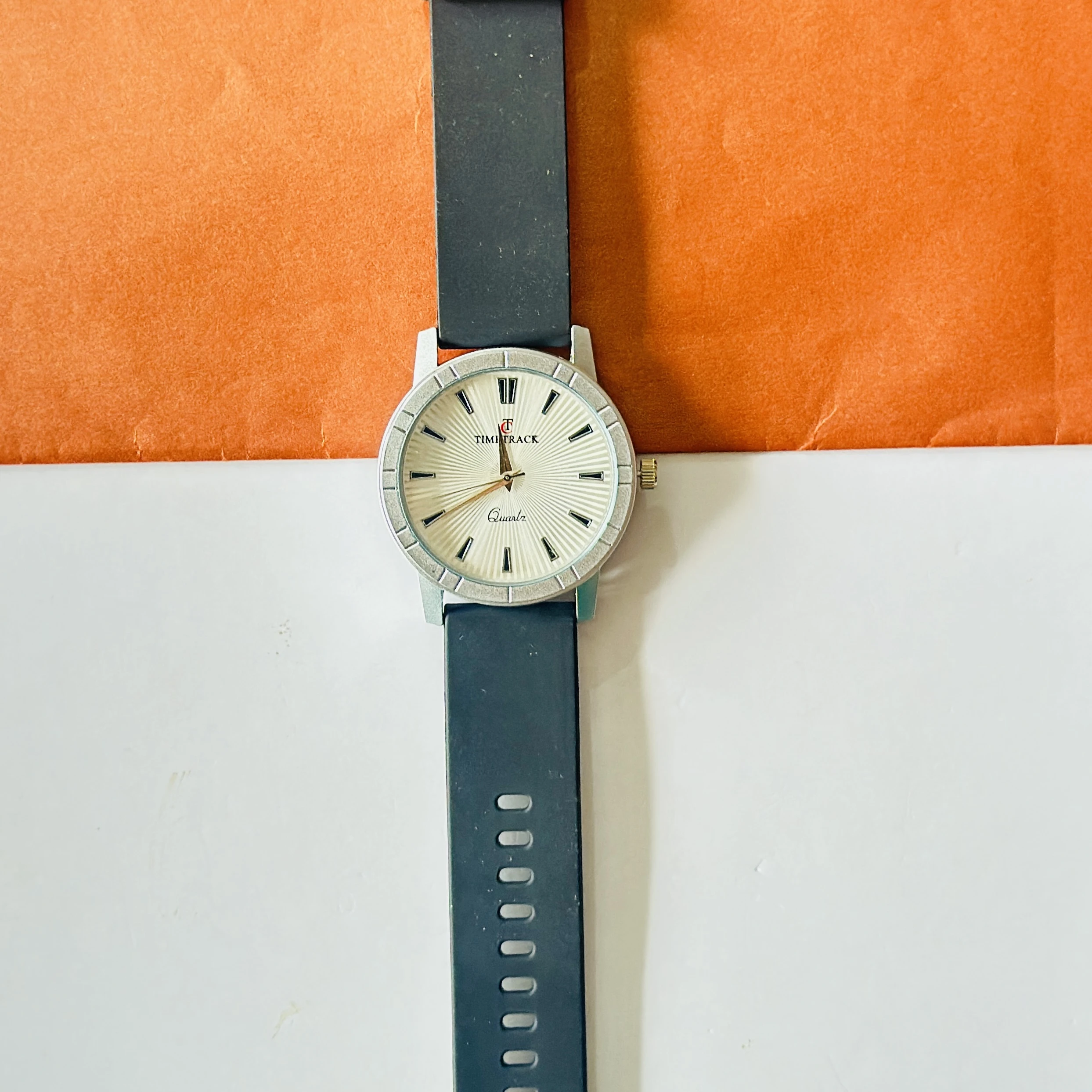 Timitrack brand quartz analog wristwatch with a silver-toned dial and a black silicone strap.