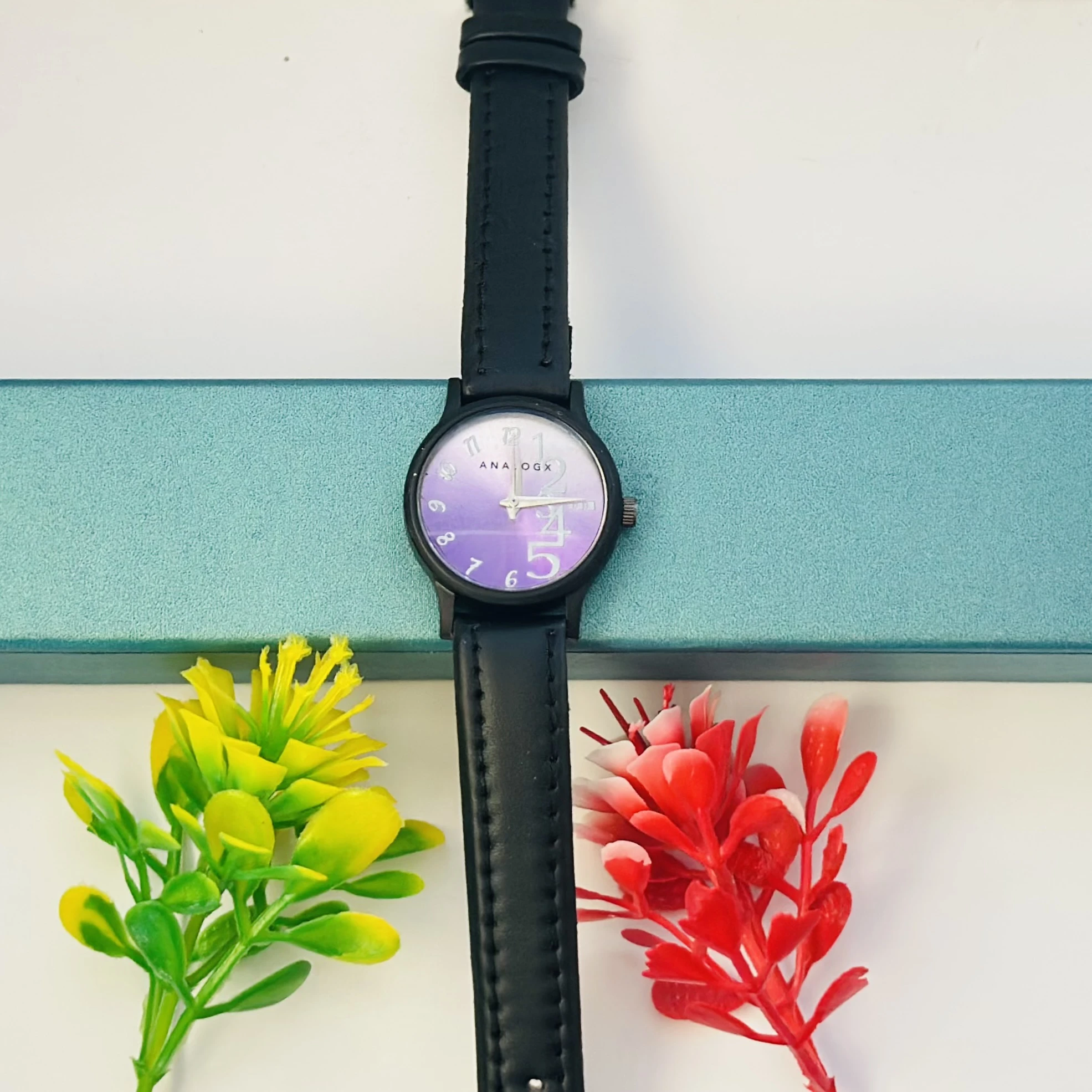 purple analog watch with a black leather strap.