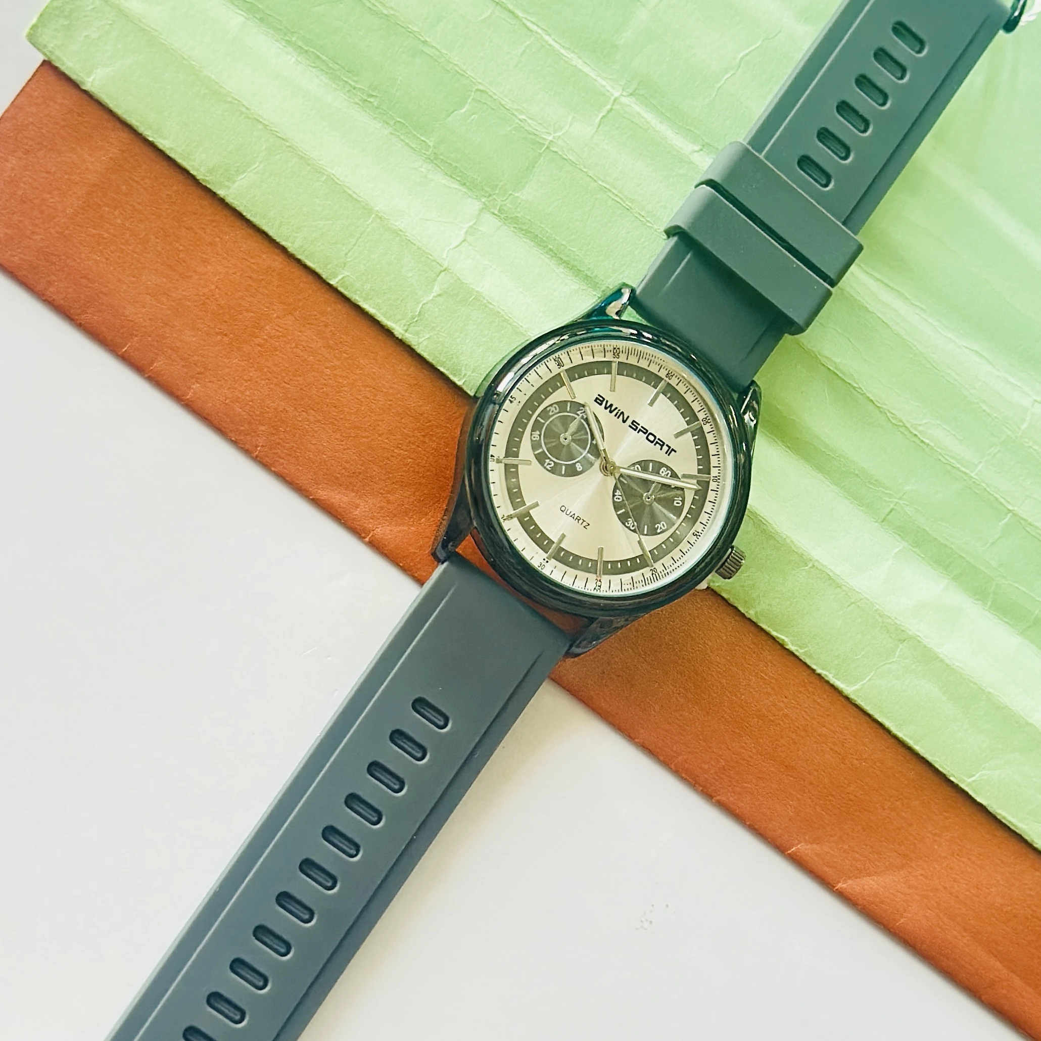 watch features a black dial with sub-dials and a green silicone strap.
