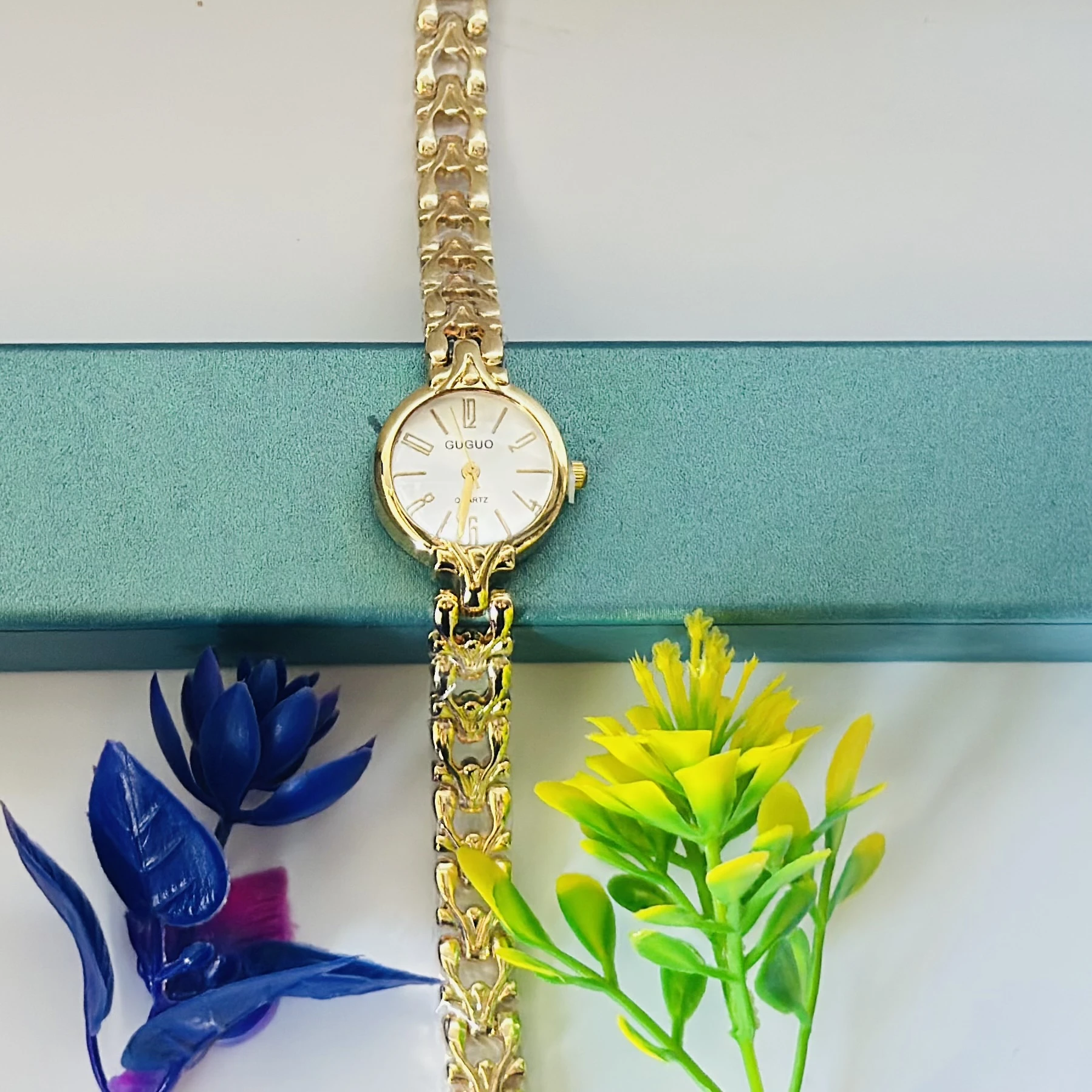 women's gold-toned analog quartz wristwatch with a metal strap.