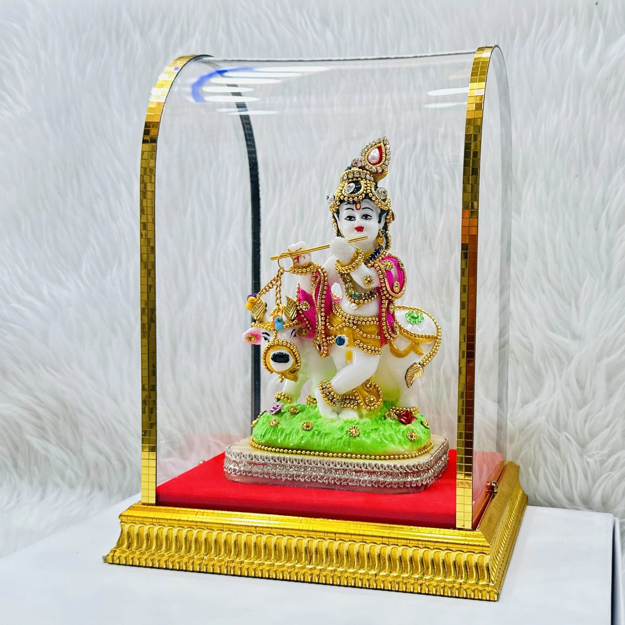 Lord Krishna and a cow housed within a protective glass case.