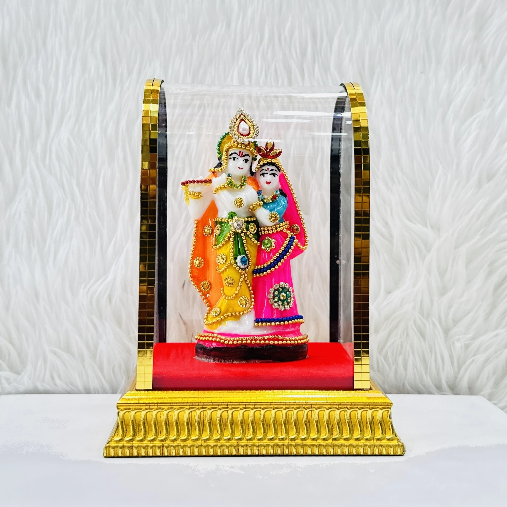 Radha Krishna statue enclosed in a protective glass case.