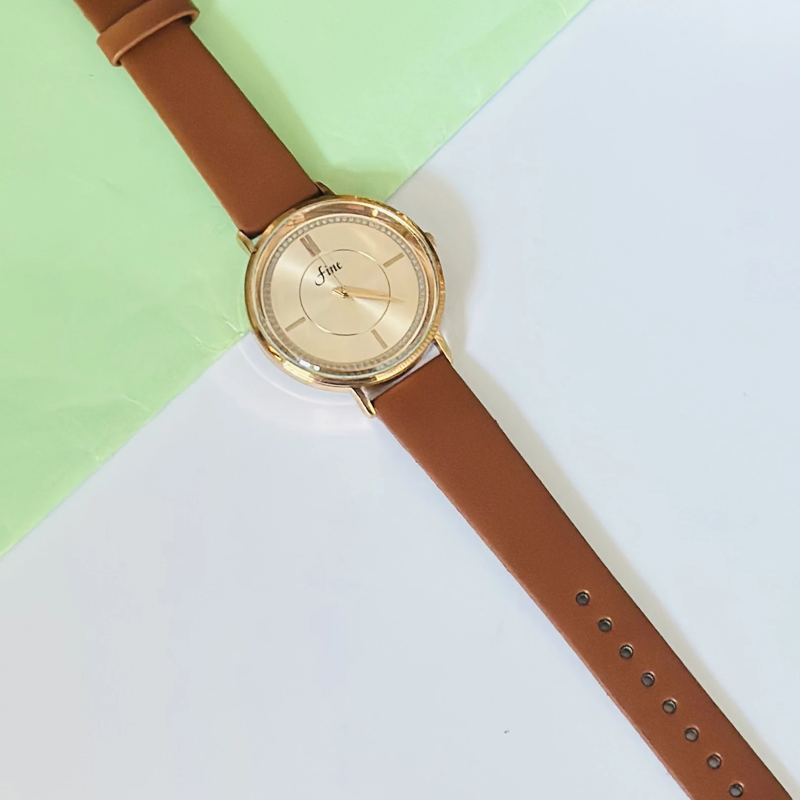 Gold tone analog wrist watch with a brown leather strap