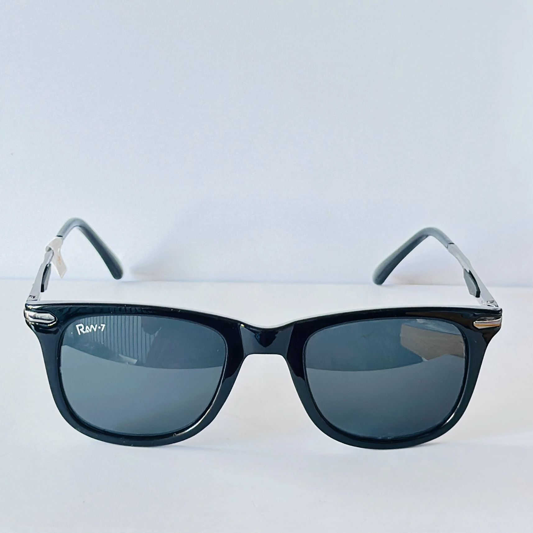 Black sunglasses appear to be similar to the iconic Ray-Ban Original Wayfarer.