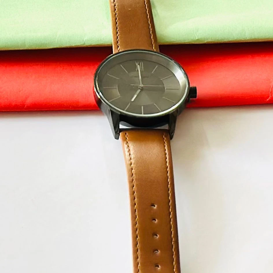 round analog watch with a brown leather strap