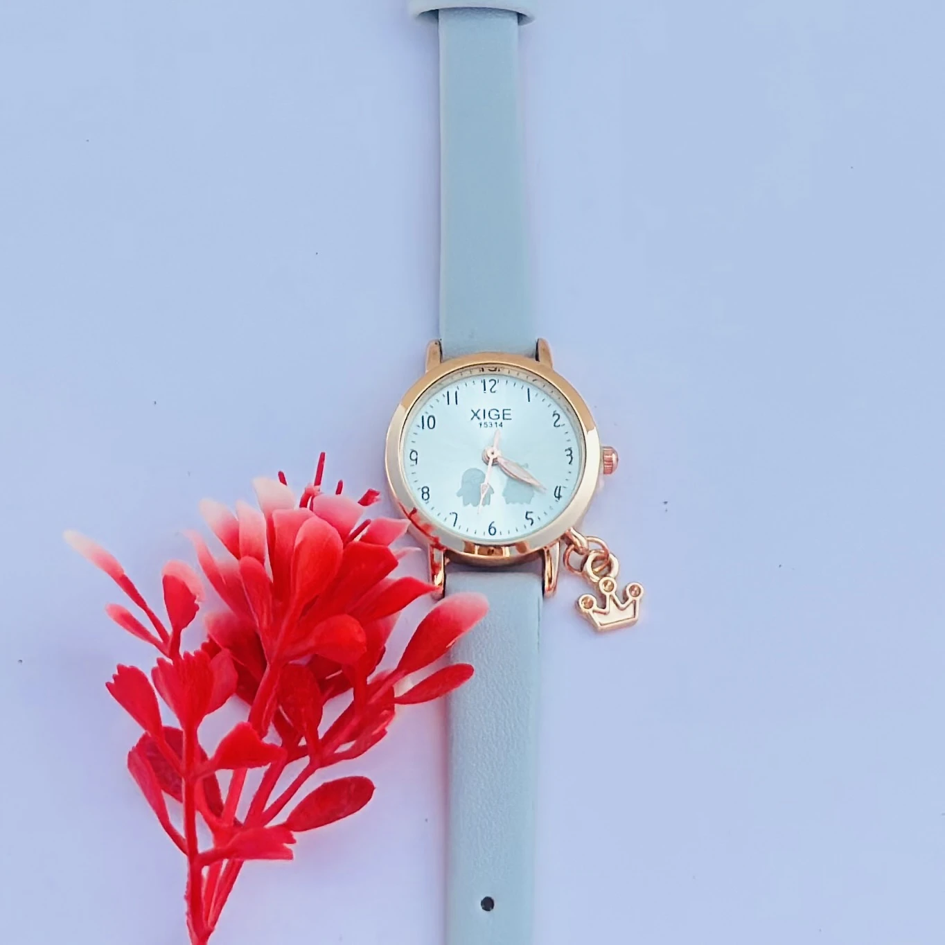 analog quartz watch with a rose gold case and a light blue leather strap featuring a horse charm.