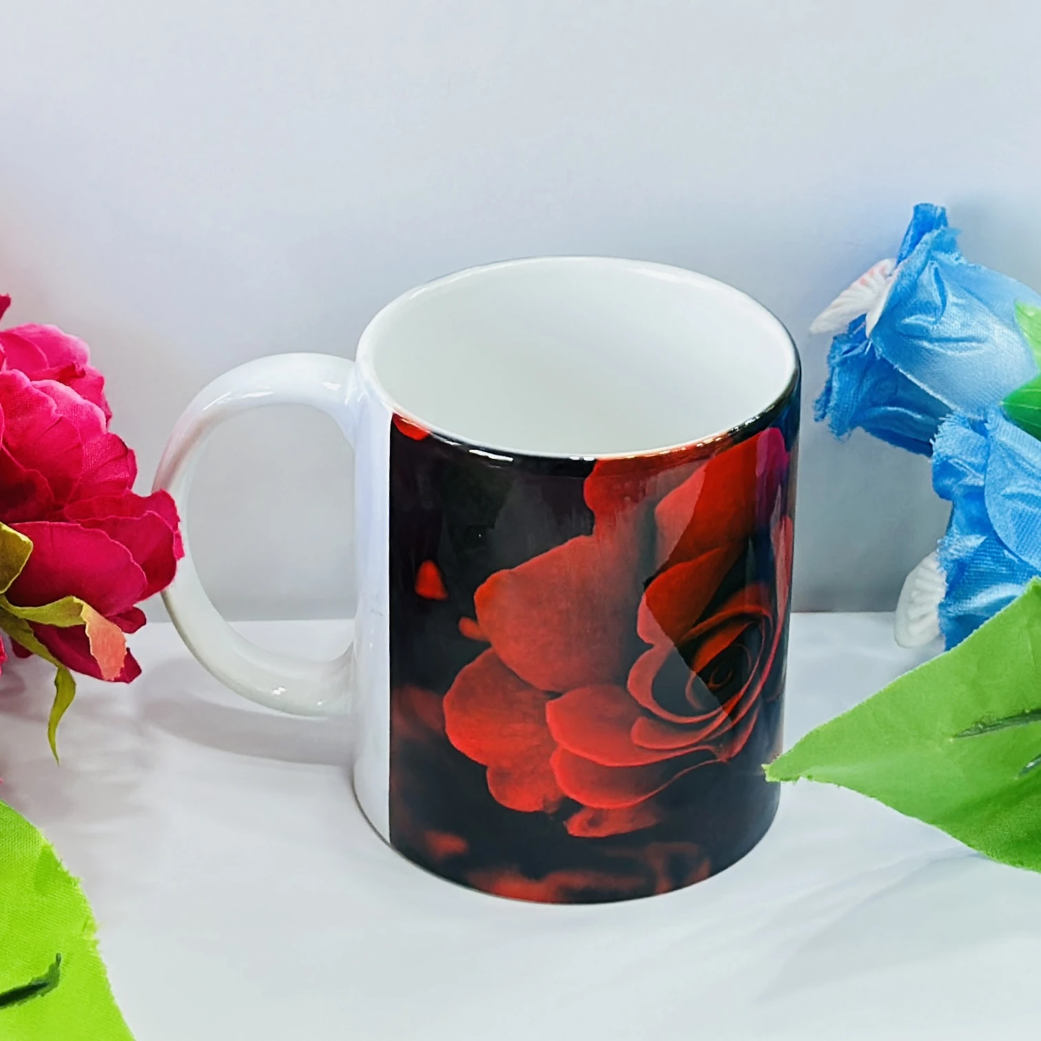 Black ceramic coffee mug with a red rose design.……33J49Y
