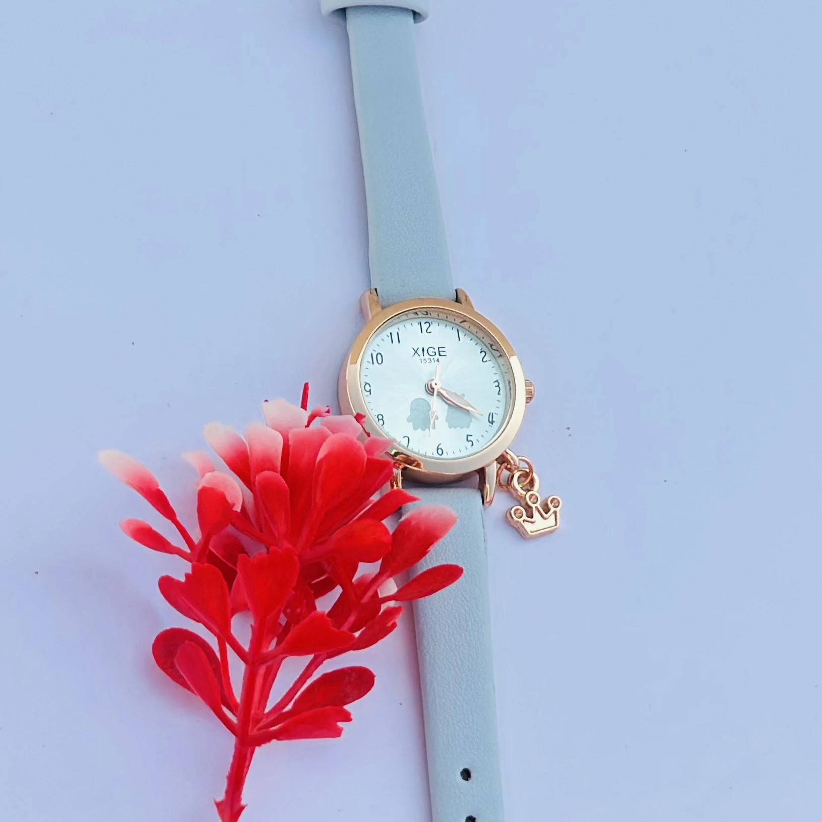 analog quartz watch with a rose gold case and a light blue leather strap featuring a horse charm.