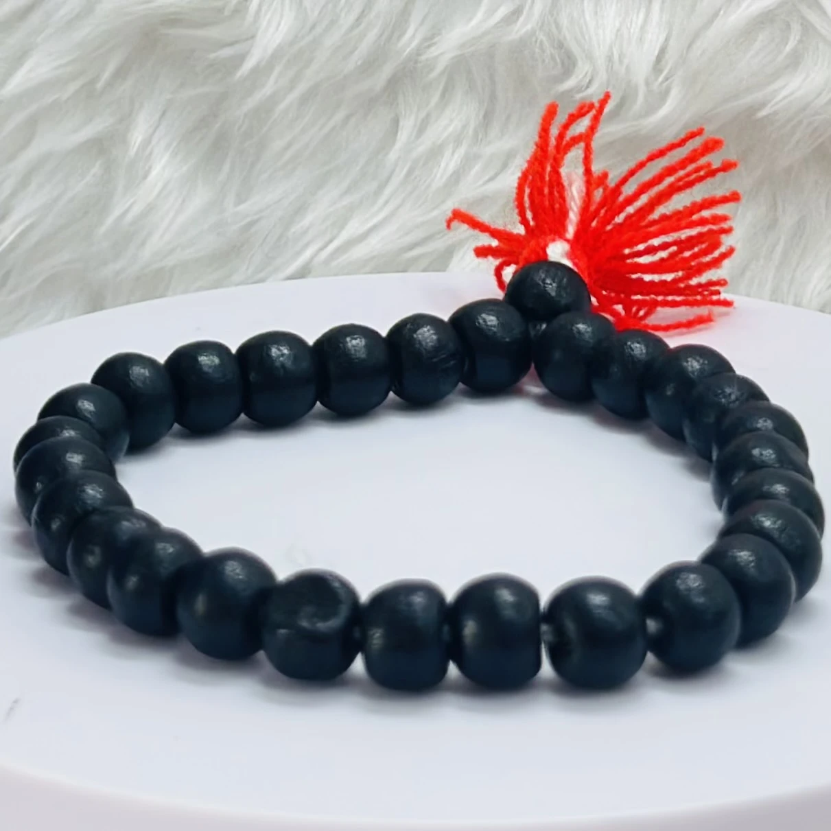 Black onyx or blackwood beaded bracelet with a red tassel.