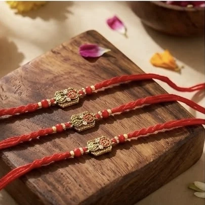 set features traditional red moli threads paired with ornate gold-toned charms, likely depicting a Ganesha or Swastik design