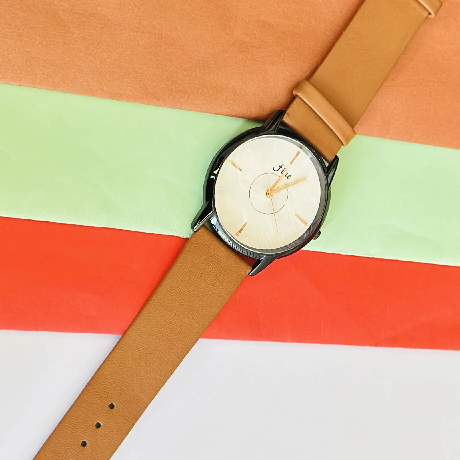 Analog wrist watch with a brown leather strap.