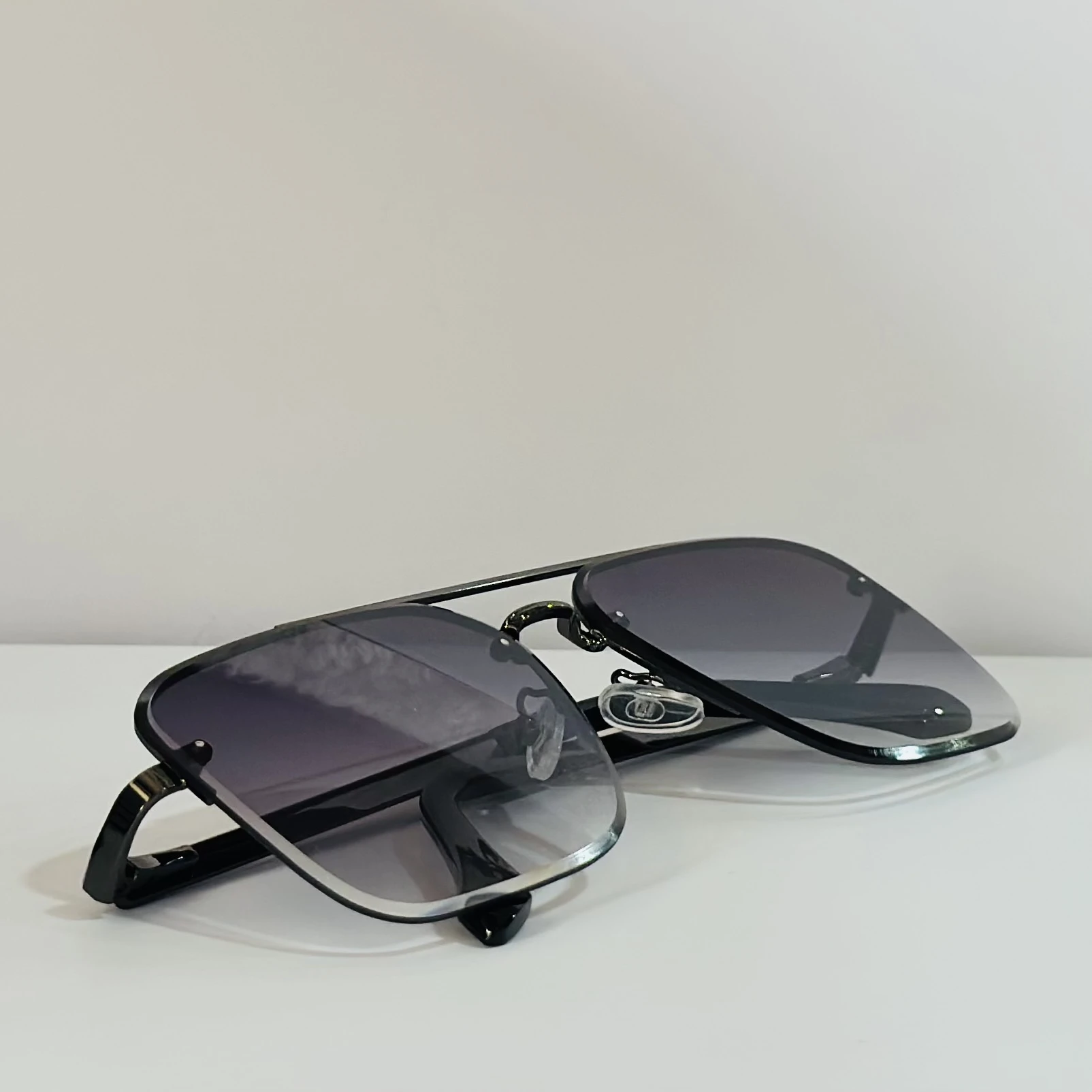 pair of aviator-style sunglasses with a black metal frame and grey gradient lenses.