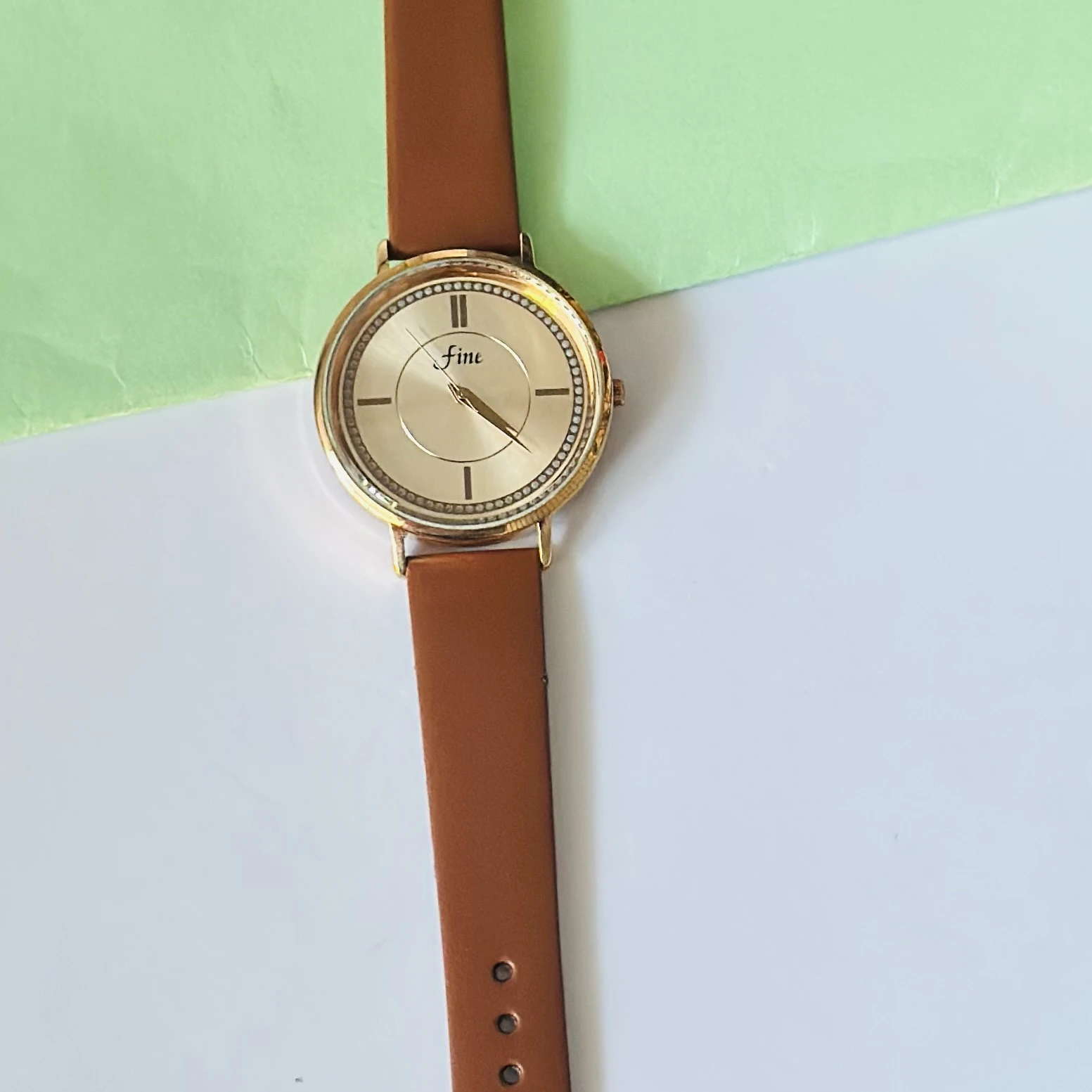 Gold tone analog wrist watch with a brown leather strap