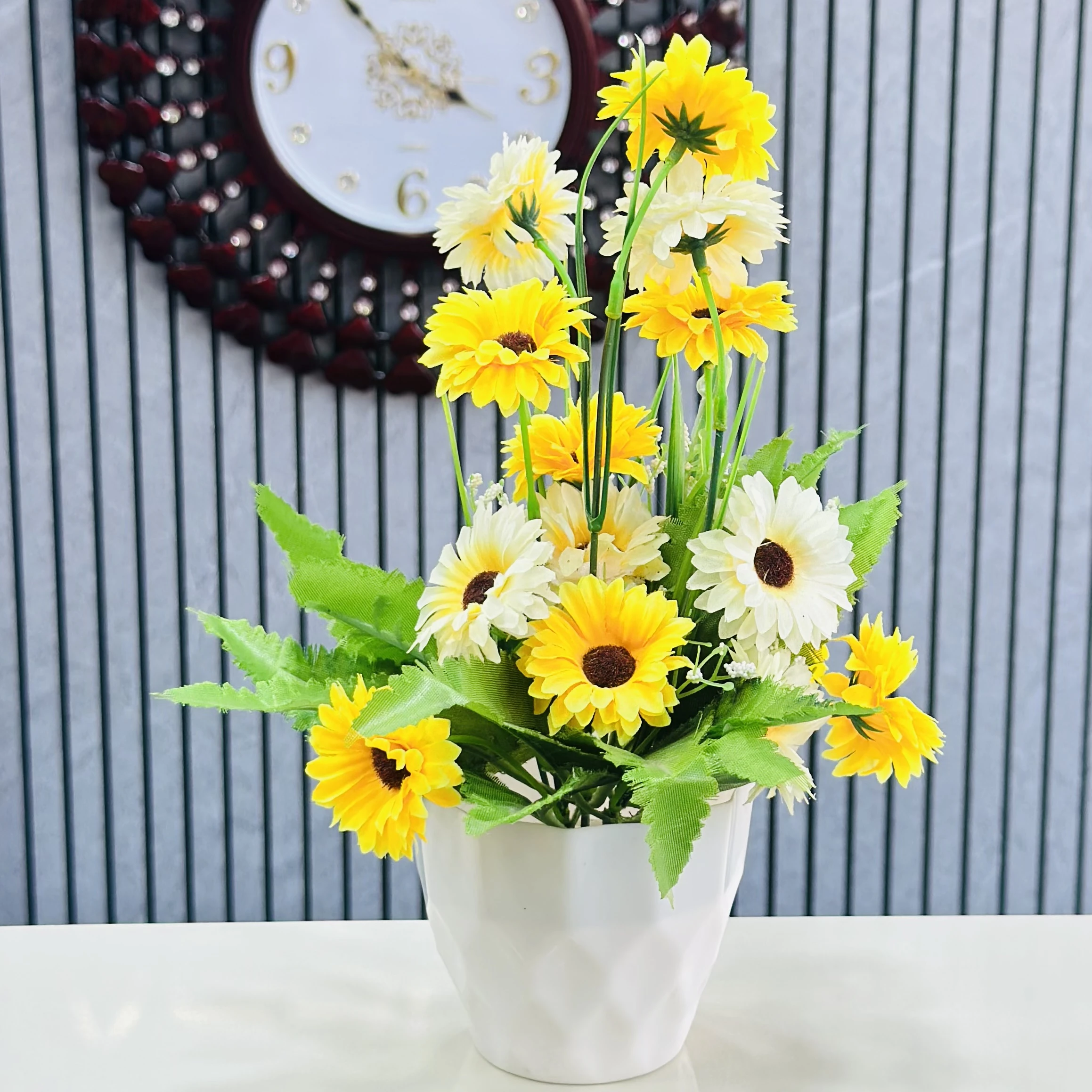 Sunflower arrangement in a white ceramic pot.