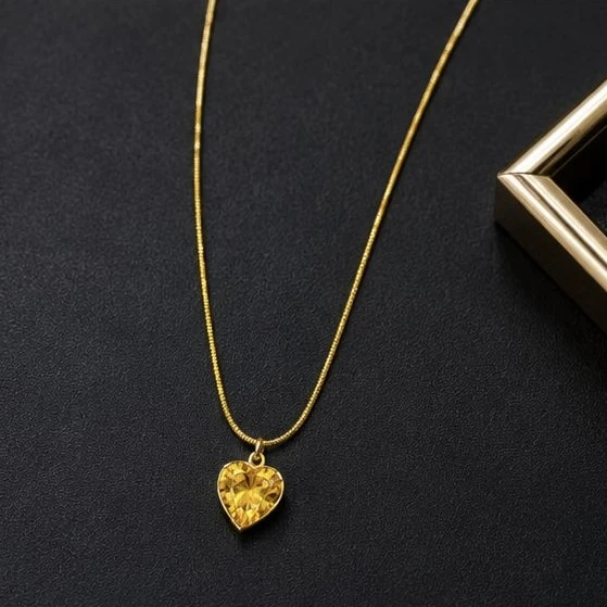 Gold plated necklace features a heart-shaped pendant with a prominent yellow gem