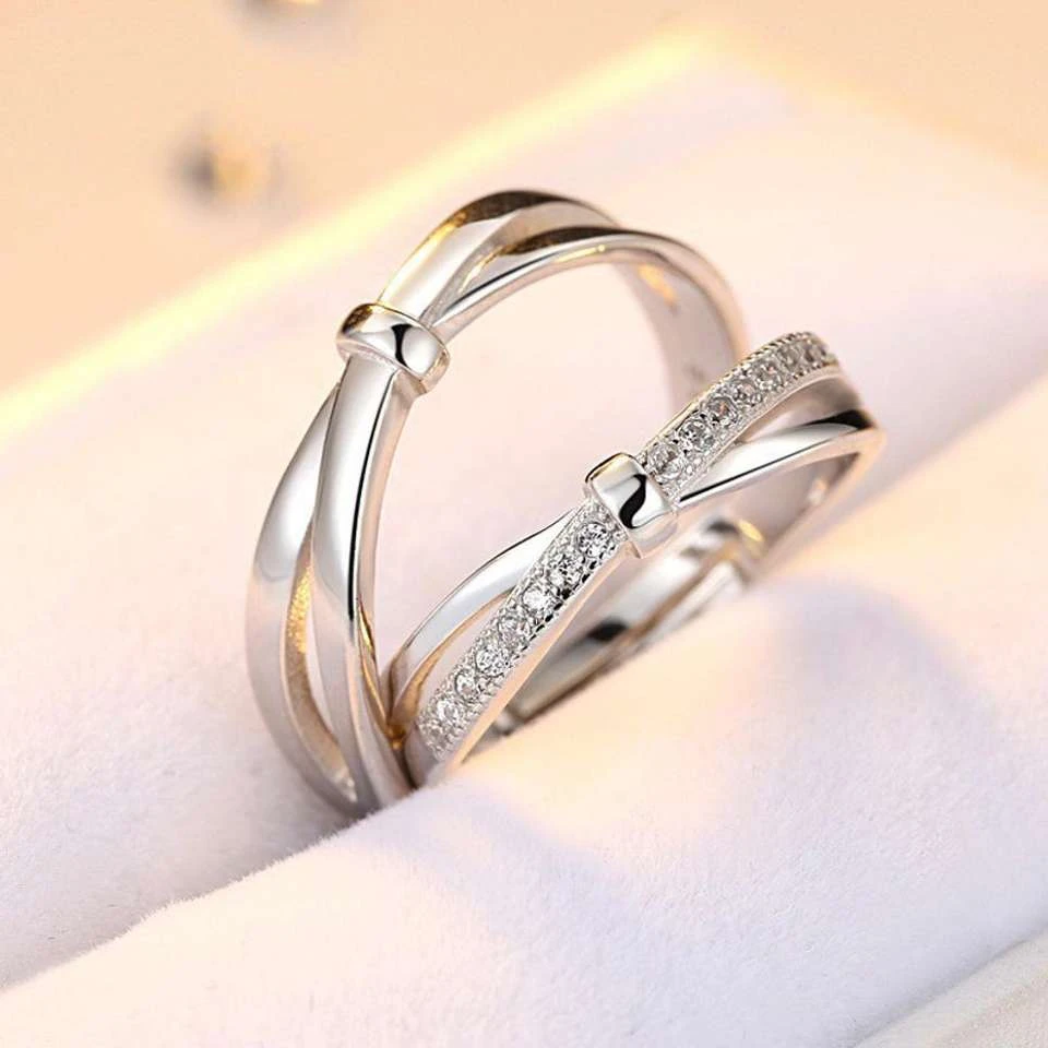 set of silver-plated, adjustable couple rings featuring a double bowknot design, with one ring studded with cubic zirconia stones.